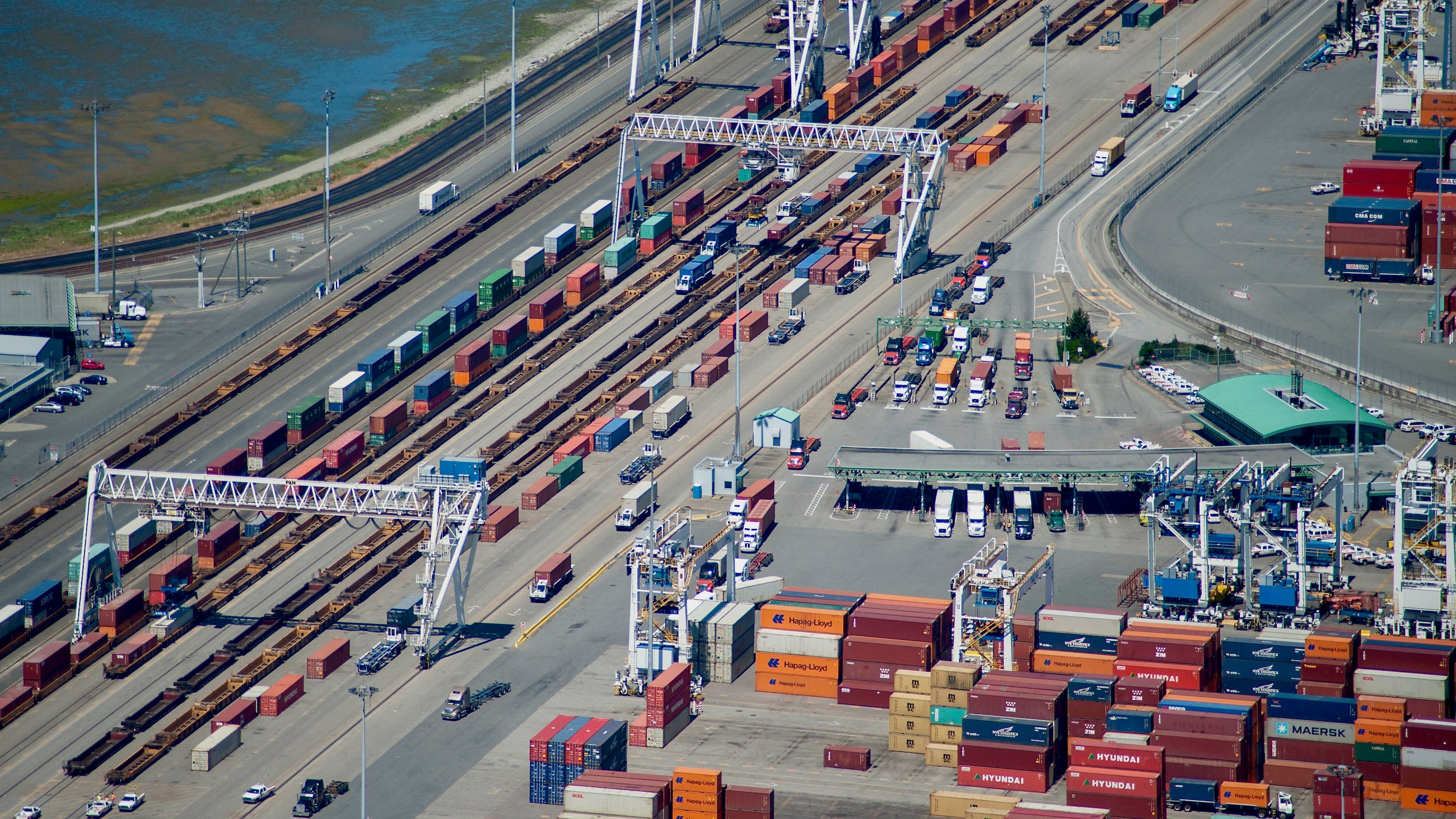 An aerial view of trucks at the Port of Vancouver, next to trains with containers.