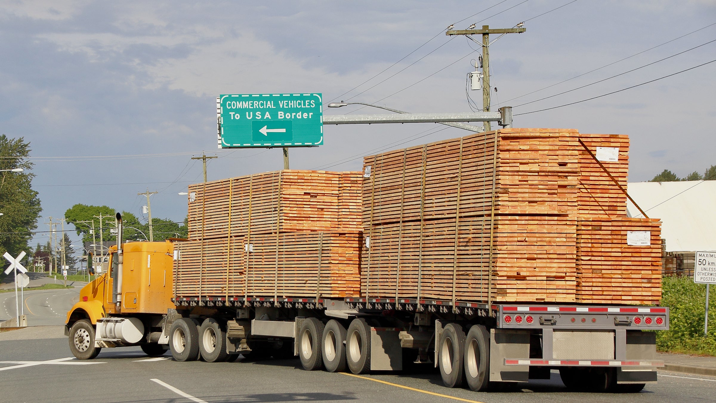 A double flatbed truck navigates to the US border delivering Canadian wood products.