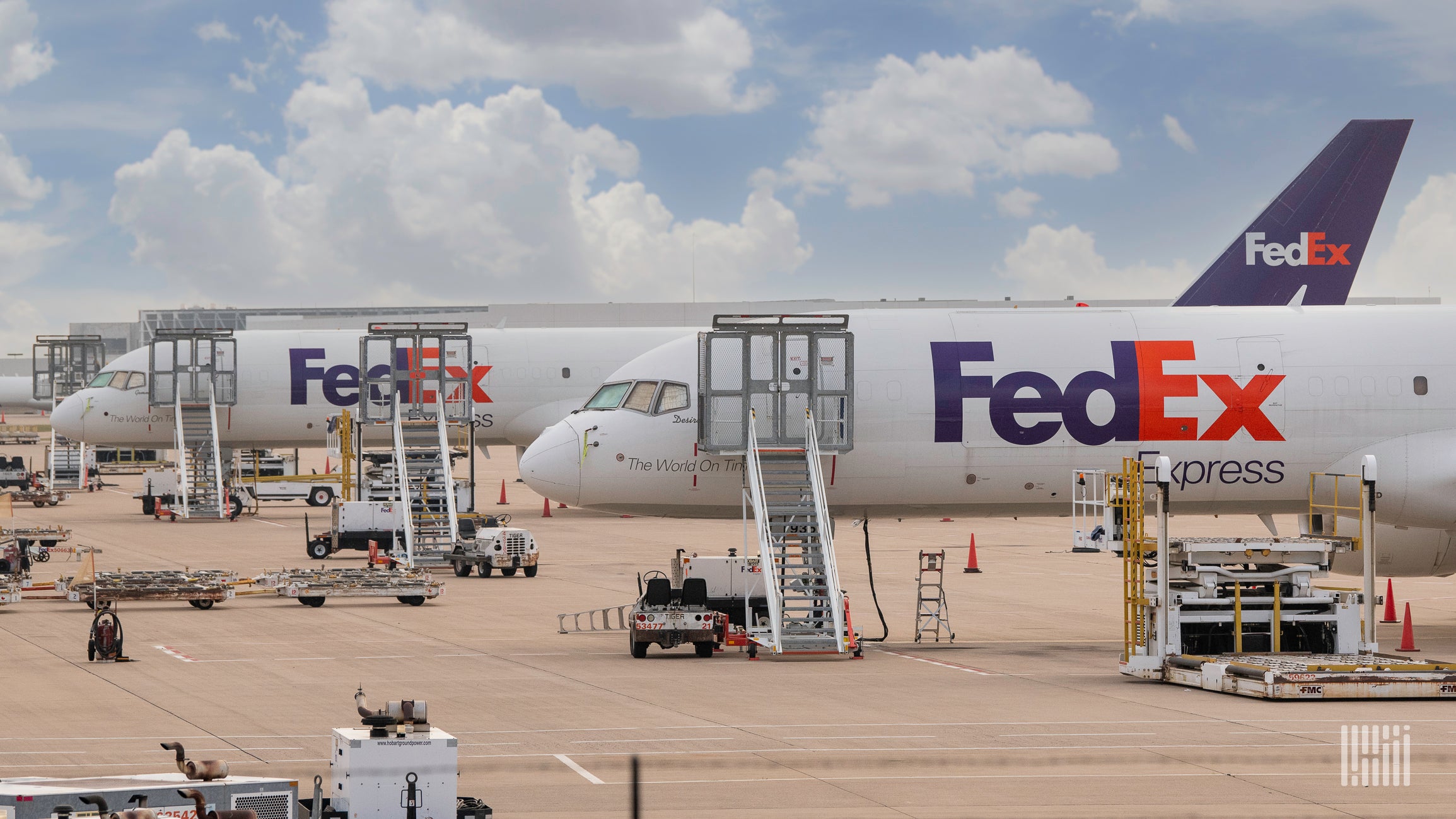 FedEx aircraft on the ground waiting to be loaded on a sunny day.