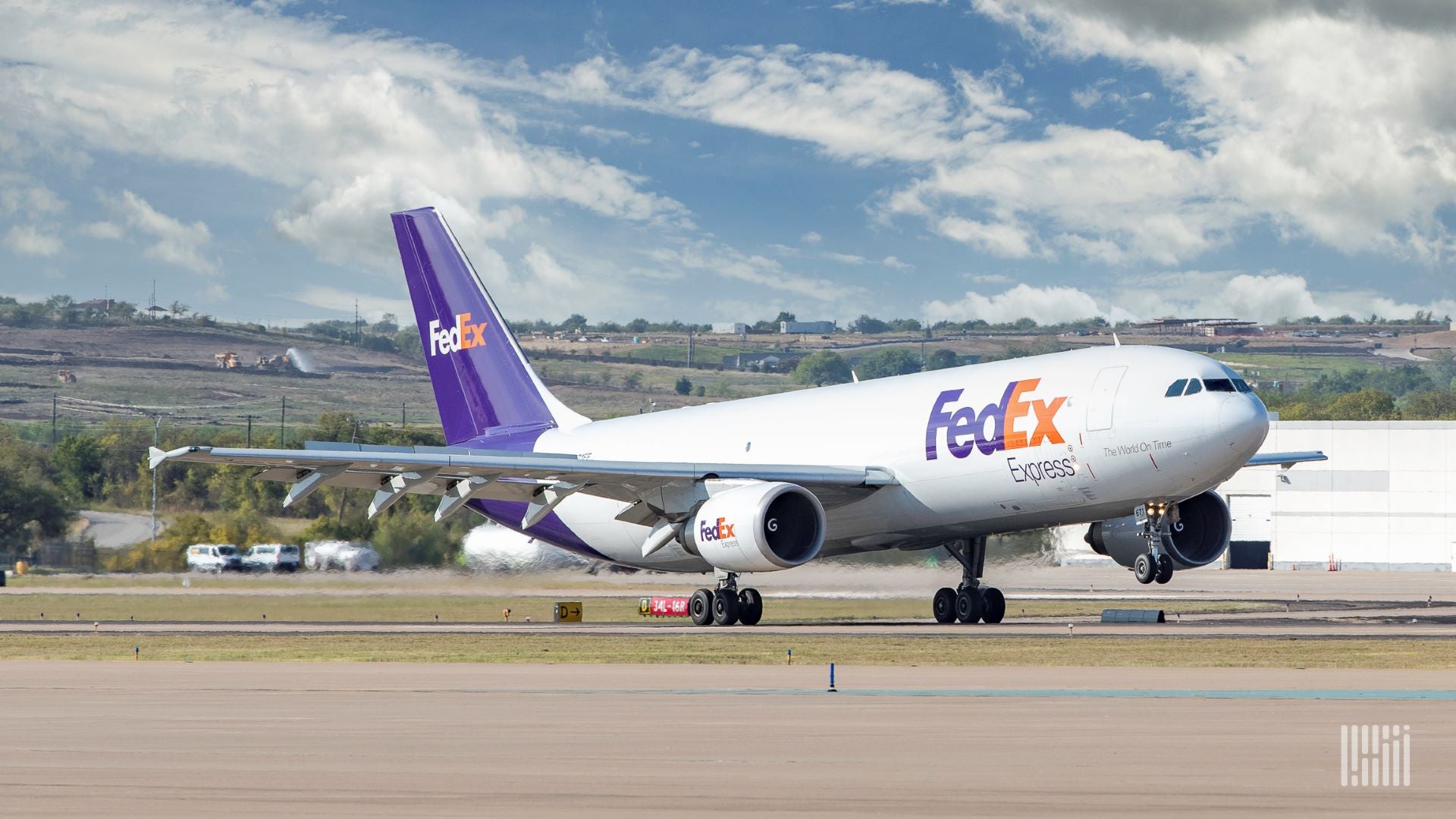 A FedEx Express plane with white fuselage and purple tail touches down on runway. fting off.