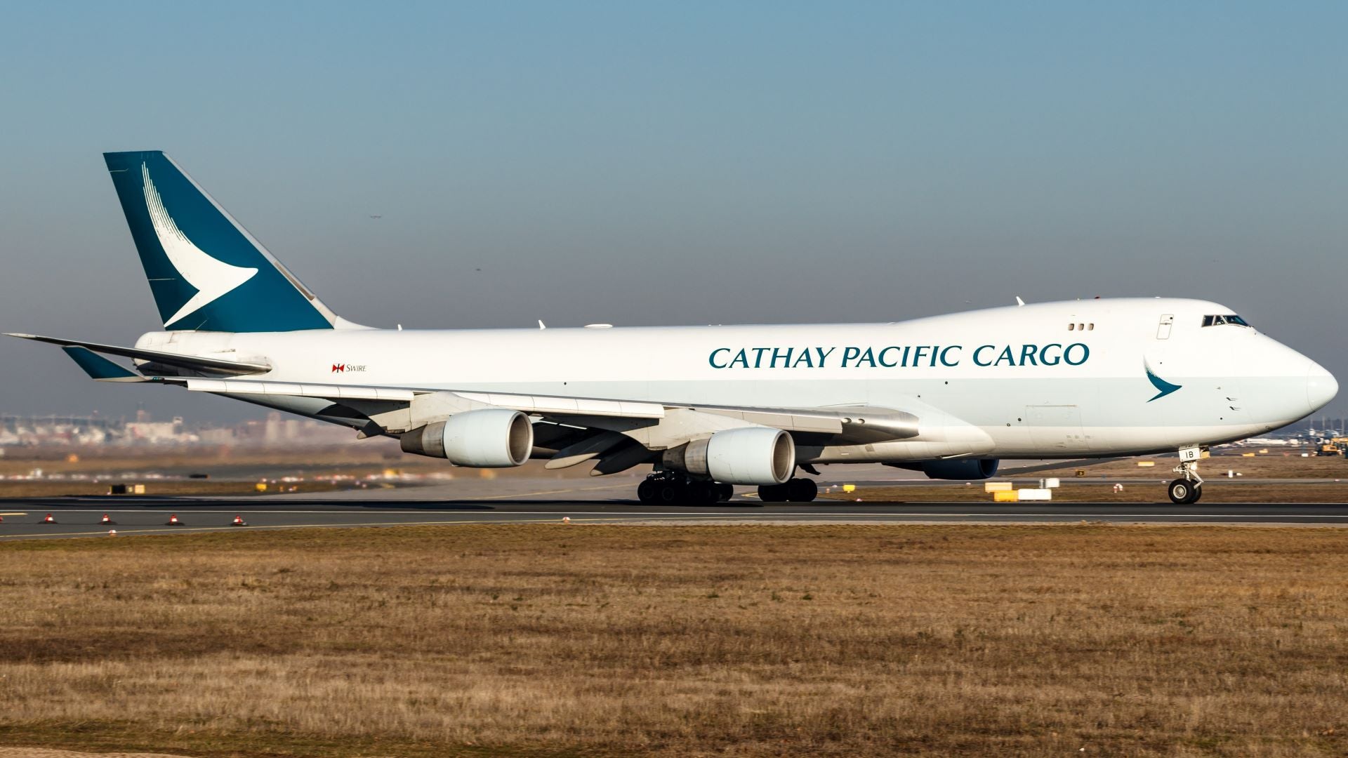 A white jumbo jet with teal colored tail and Cathay Pacific Cargo lettering.