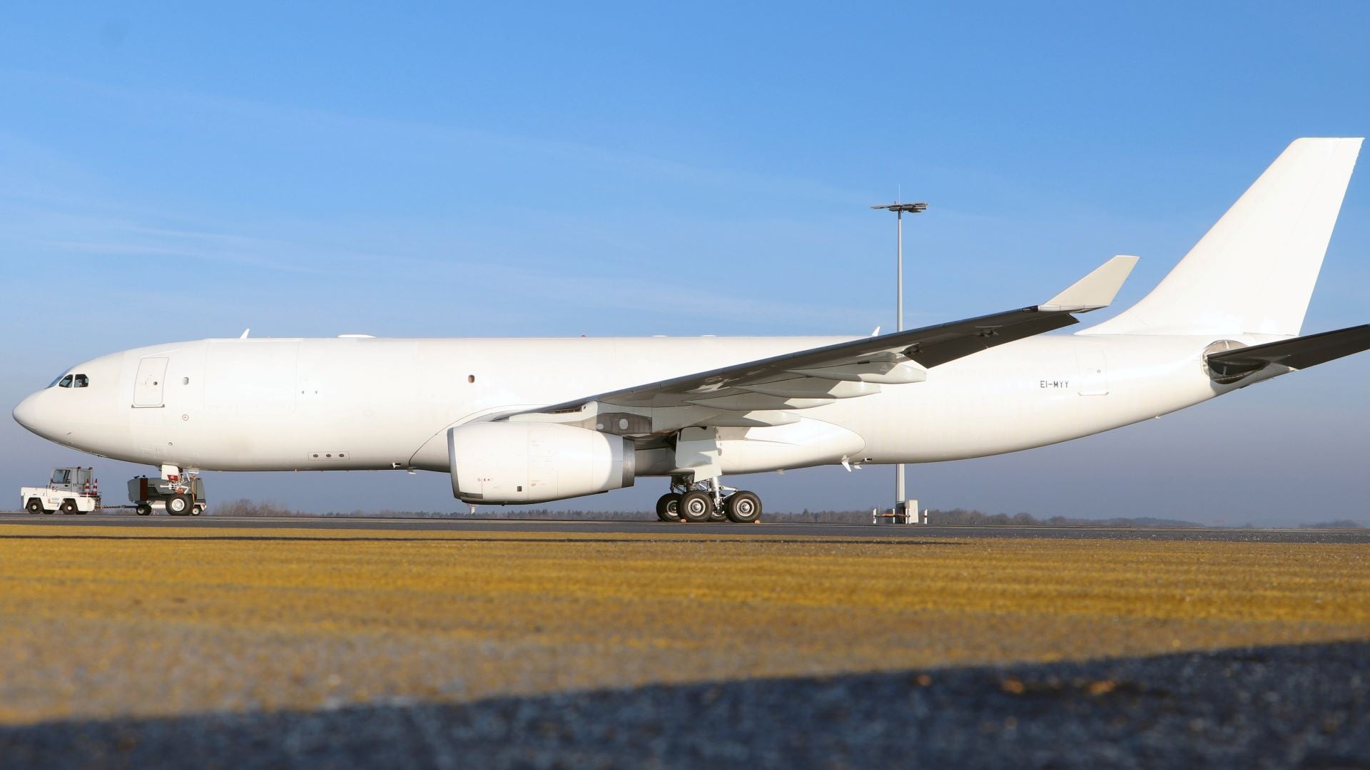 A white cargo jet sits on the field. It has no markings yet after recently undergoing a conversion.