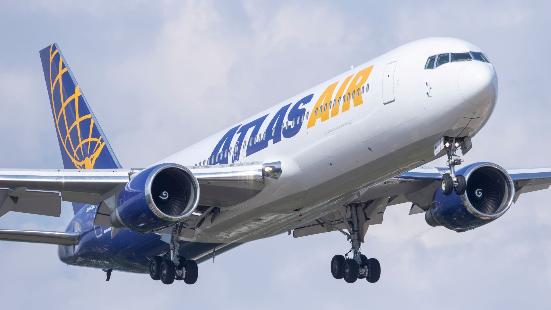 A white Atlas Air jet comes in with wheels down for landing, heading toward the camera in close up.