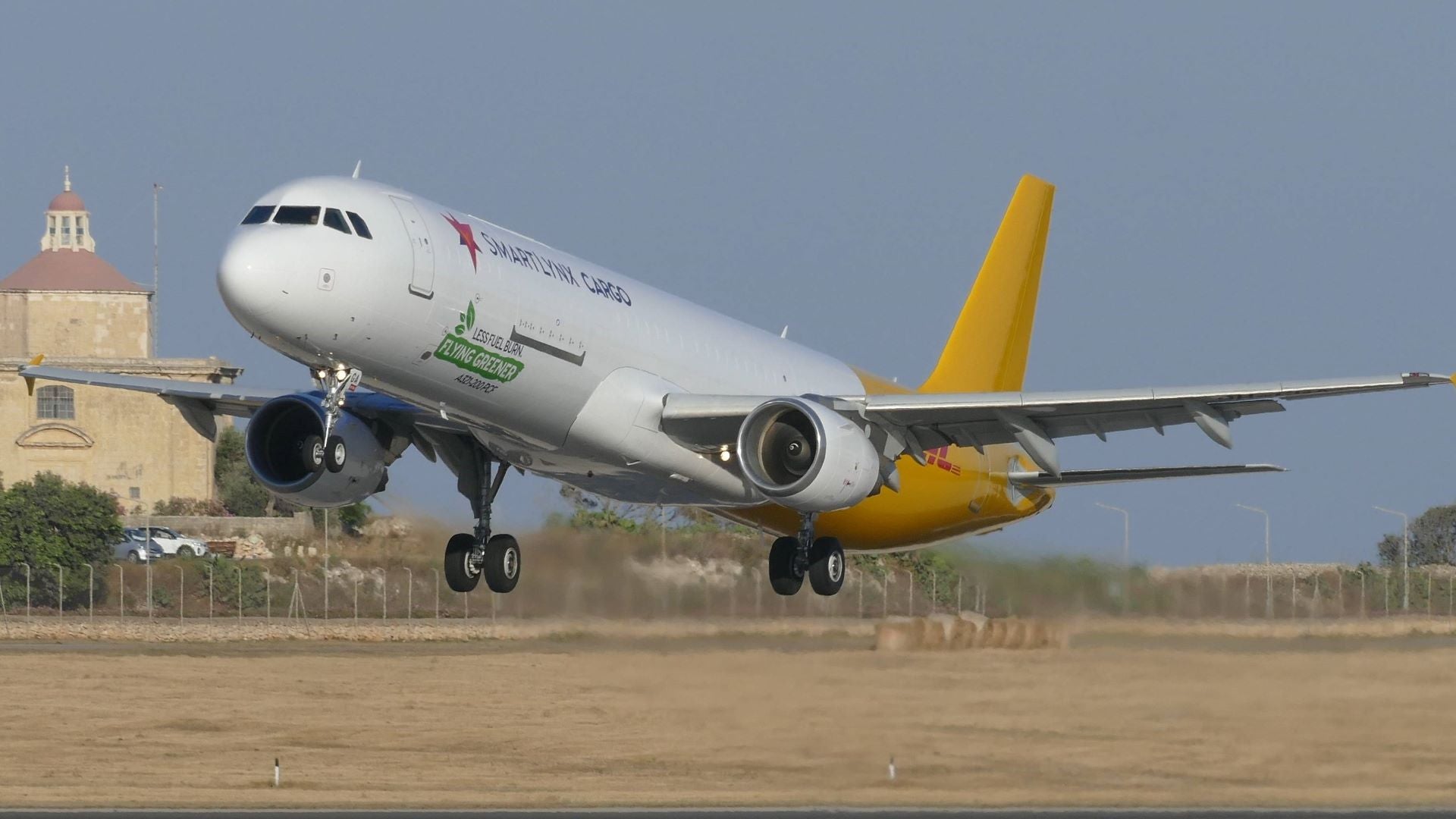 A white plane with gold rear section takes off.