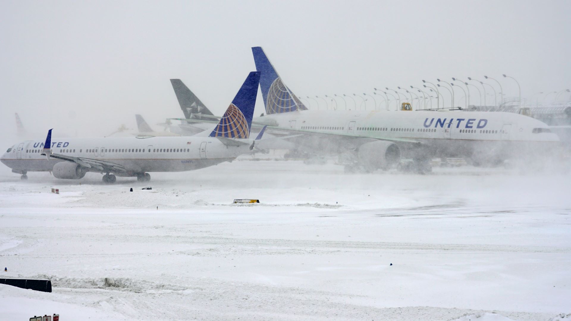 Planes on the tarmac in snowy weather.