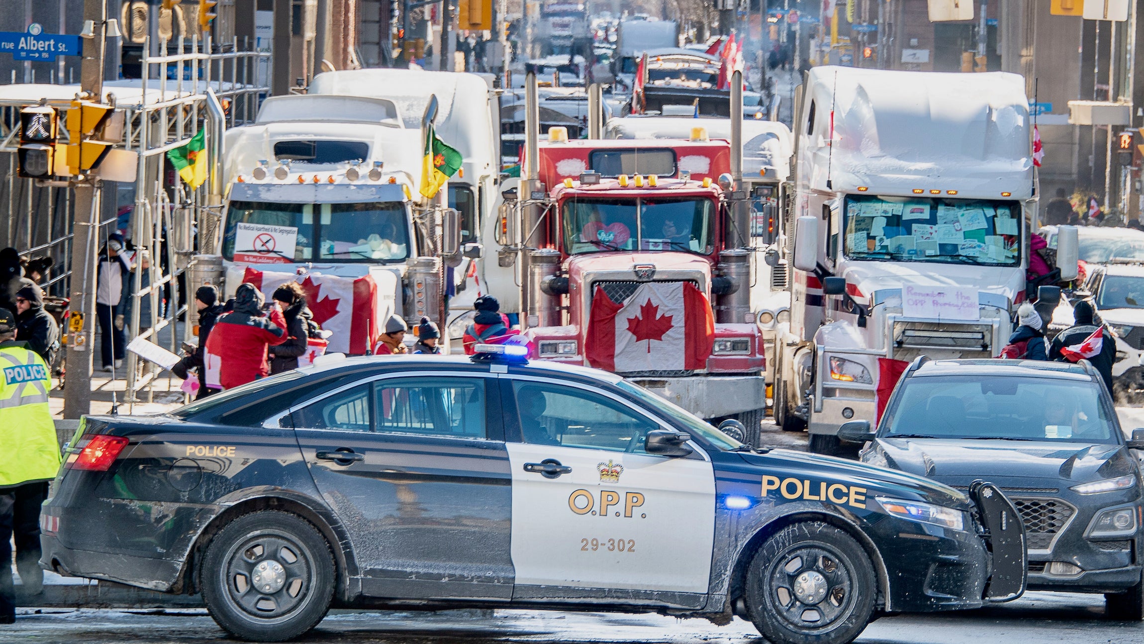 A police car is parked in front of three rows of trucks during the freedom convoy protest in Ottawa.