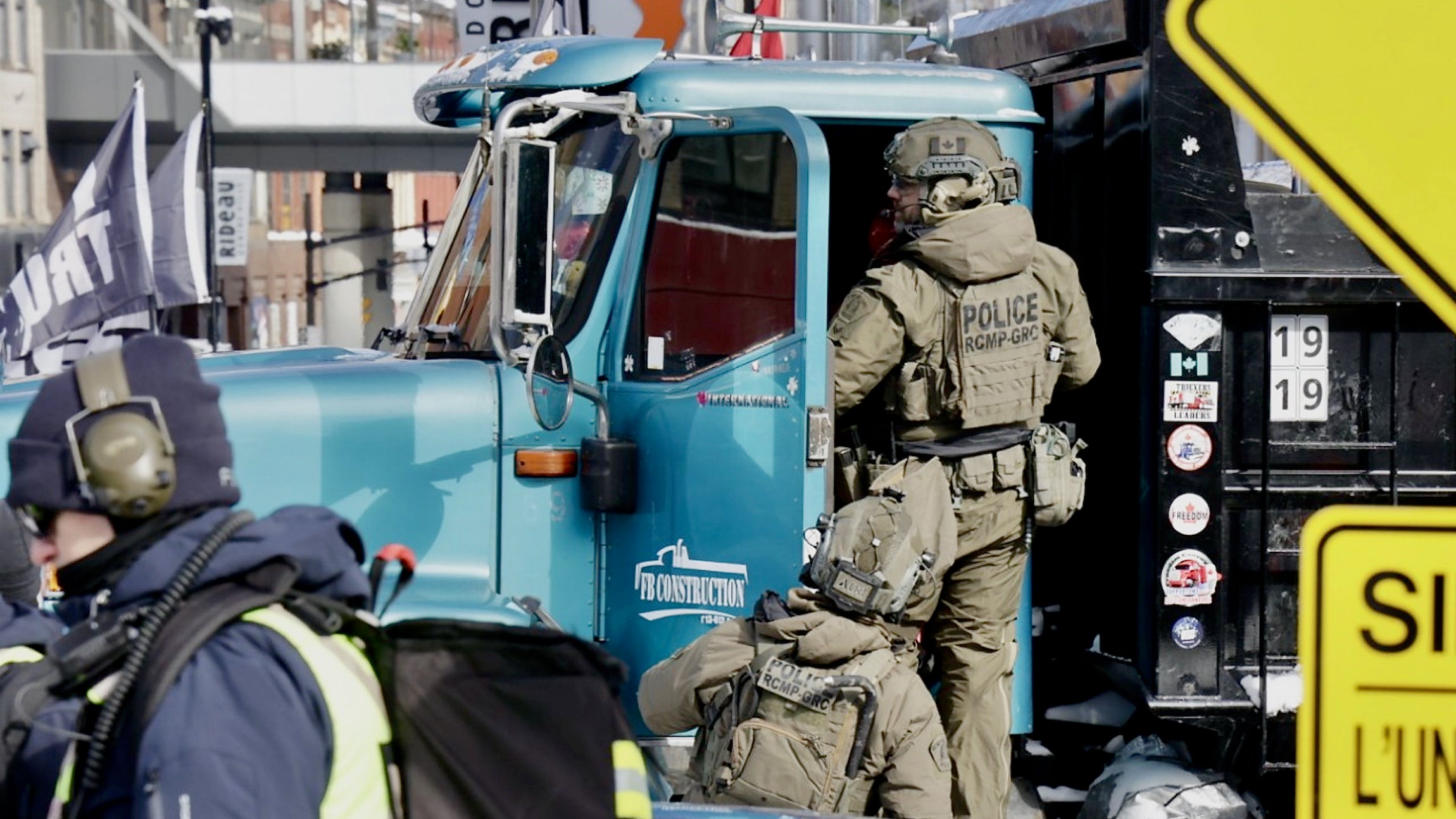 A heavily armed police officer climbs into the cab of a blue truck at the Freedom Convoy protest in Ottawa