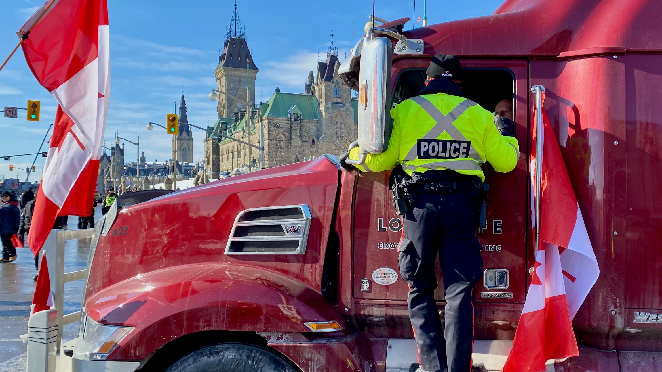 A police officer in a yellow jacket with the word "POLICE" talks to a truck driver in Ottawa, Canada.