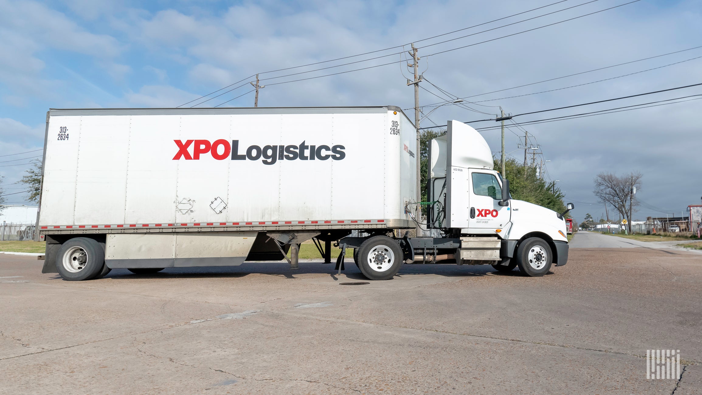 A tractor trailer with the logo of XPO Logistics on it, viewed from the side.