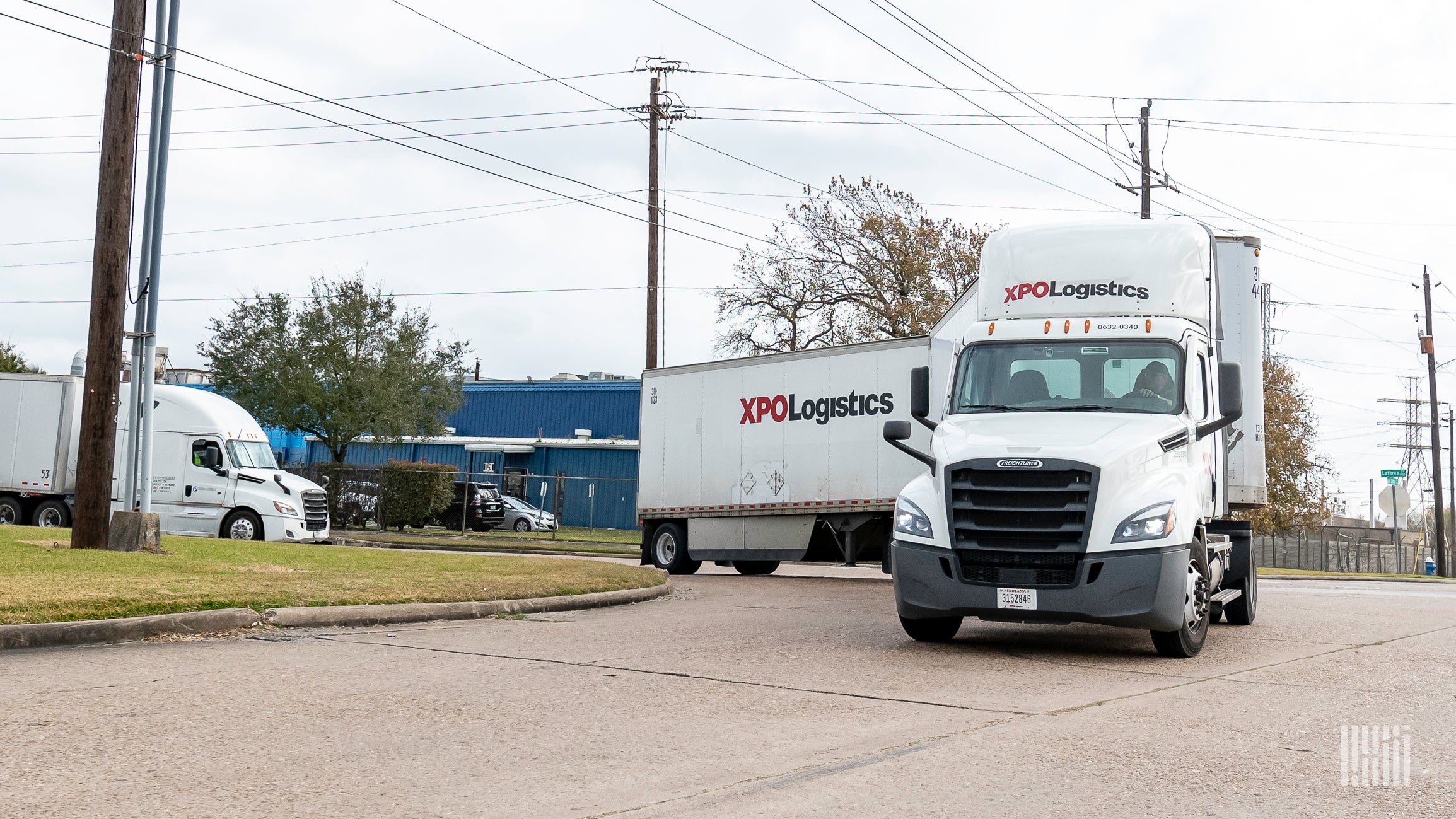 A white tractor-trailer of XPO Logistics turning around a corner.