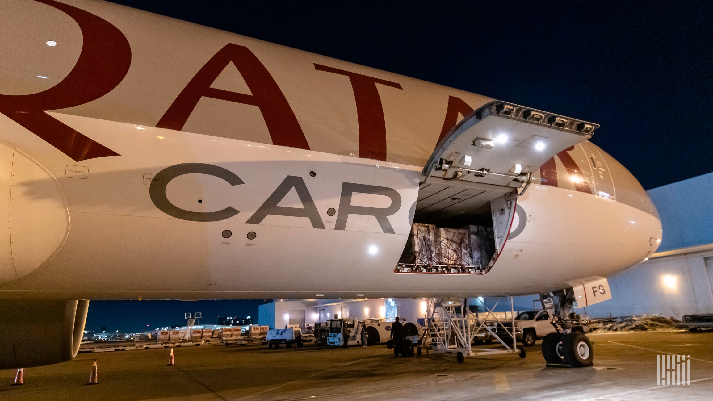 Close up of a Qatar Airways Cargo jet with side door open at night.