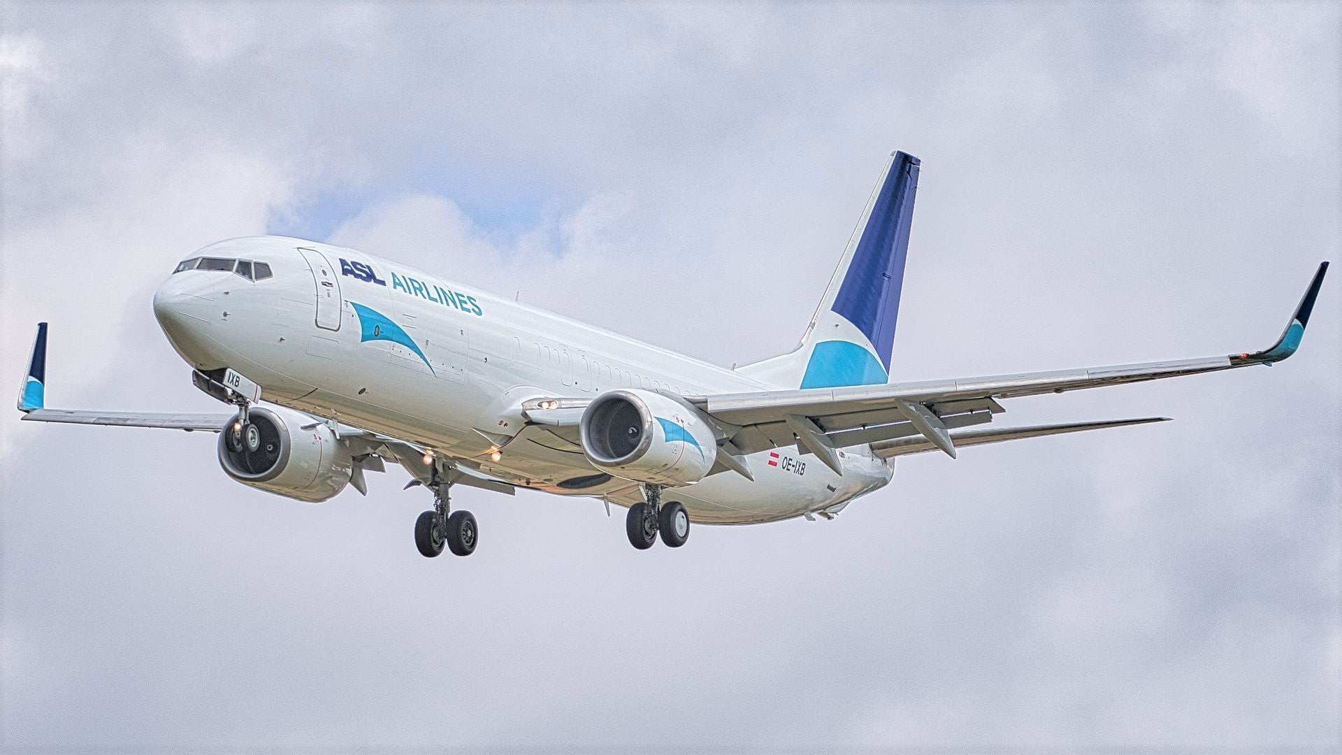 A white cargo jet with curved wing tips and blue tail comes in for landing with wheels down on approach. ASL Airlines just ordered 10-to-20 aircraft converted to carry cargo.