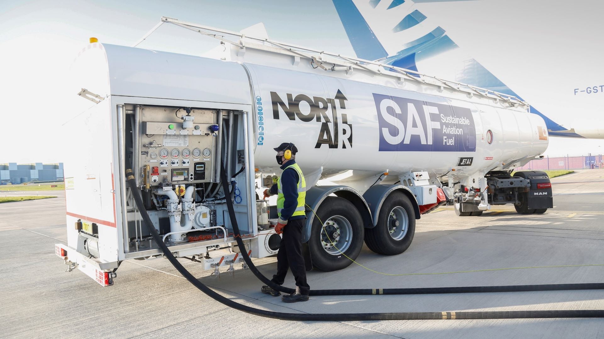 A large fuel truck with sustainable aviation fuel fills up an airplane.