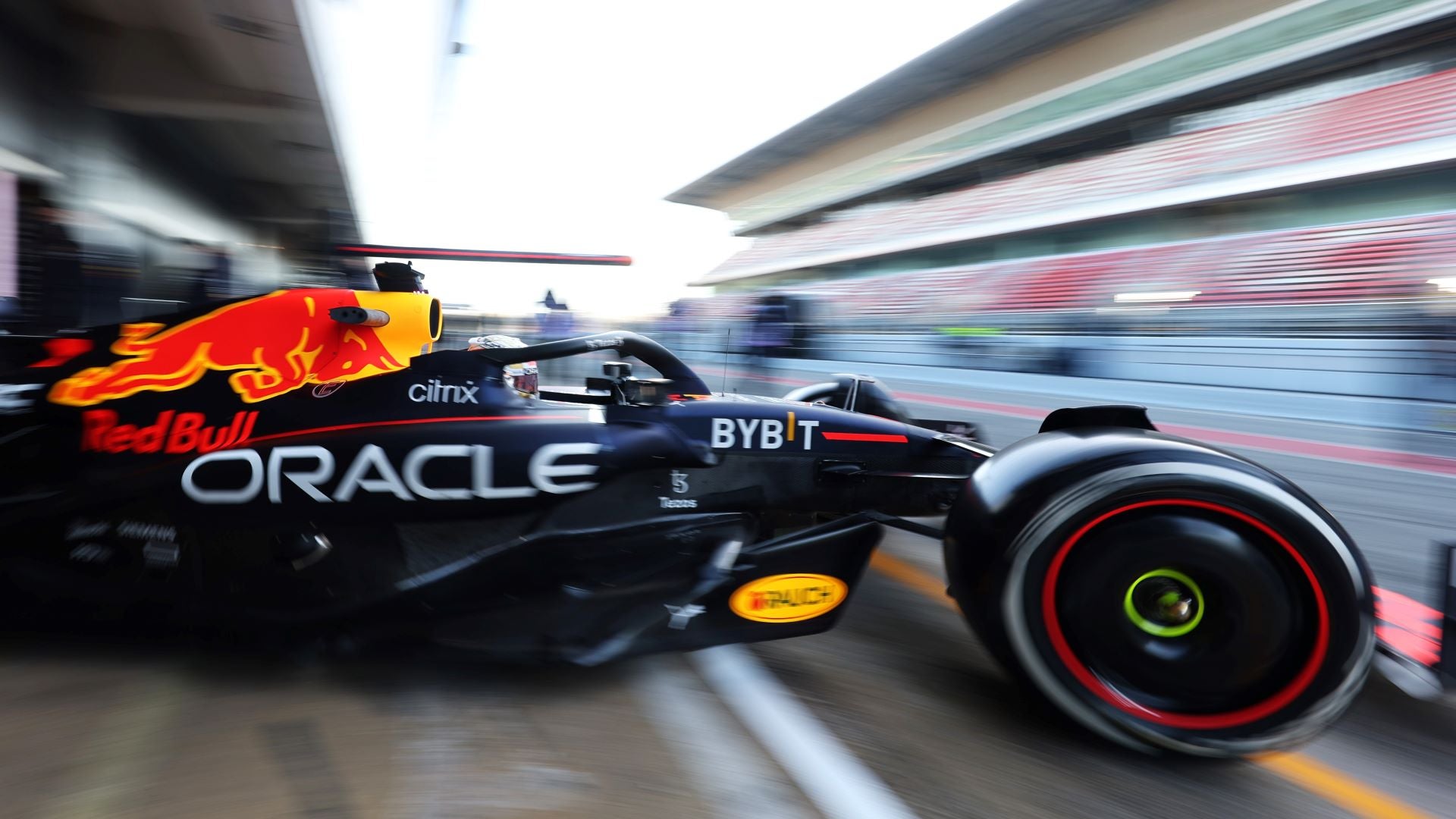 A blurred side close up of the Red Bull Formula One racing car exiting the garage.