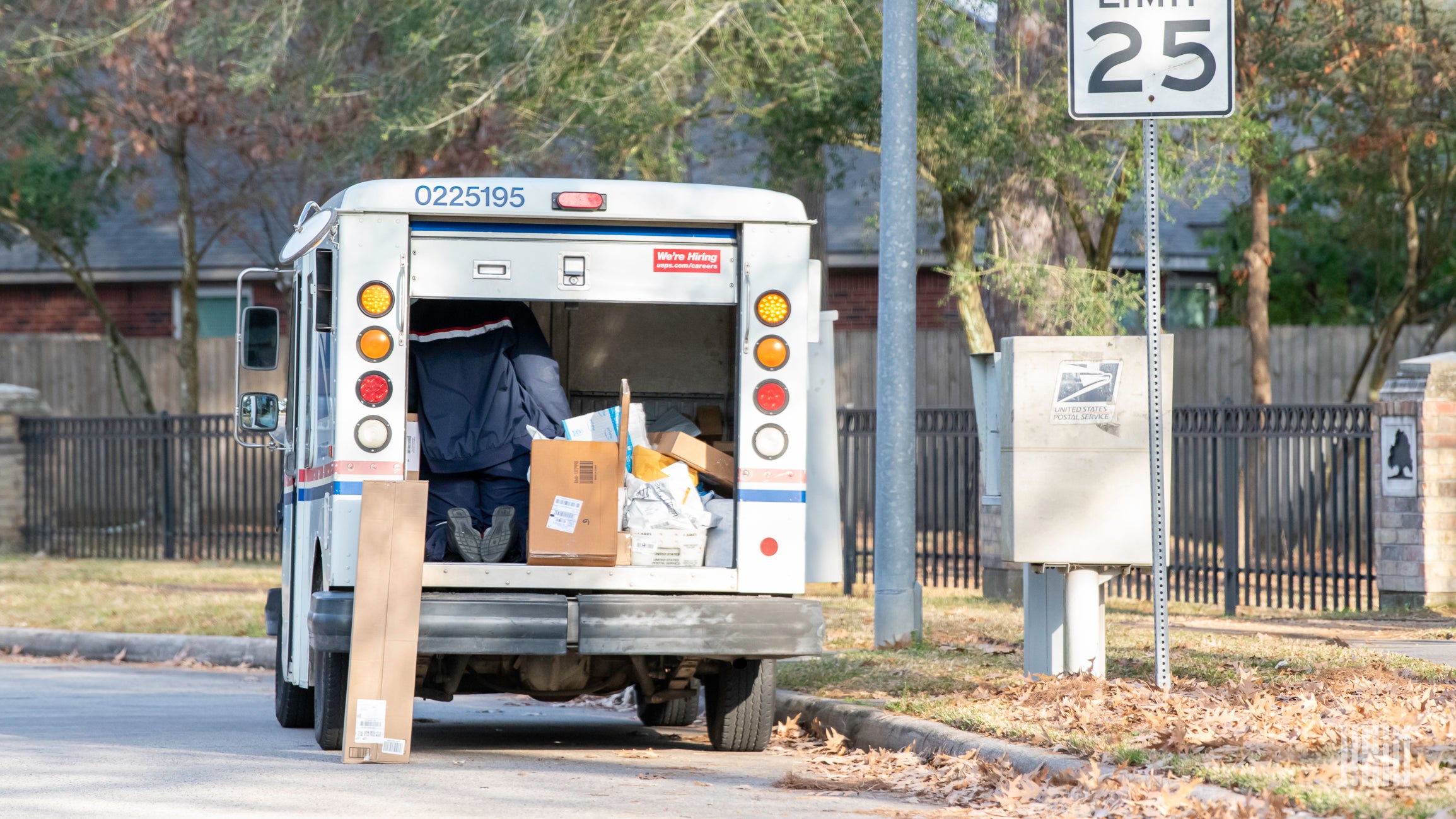 A USPS truck filled with parcels seen from behind.