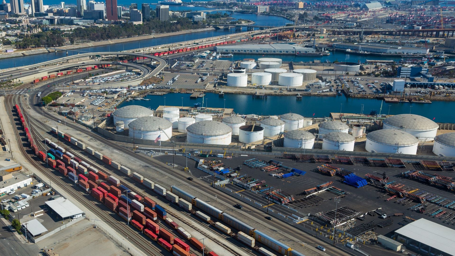 Large tank farm, rail tracks with container trains at a port. Overhead view.