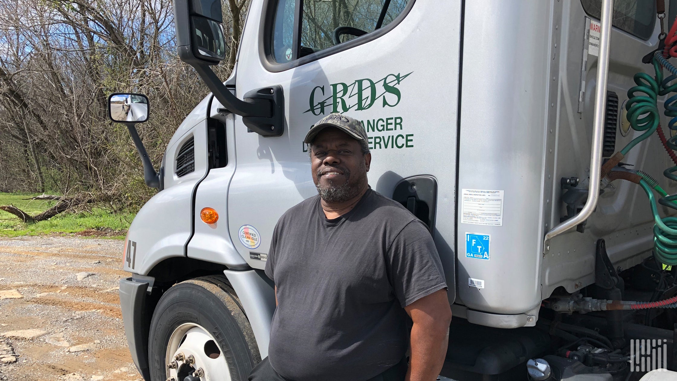 Trucker James Card standing next to his Green Ranger Delivery Service tractor-trailer.