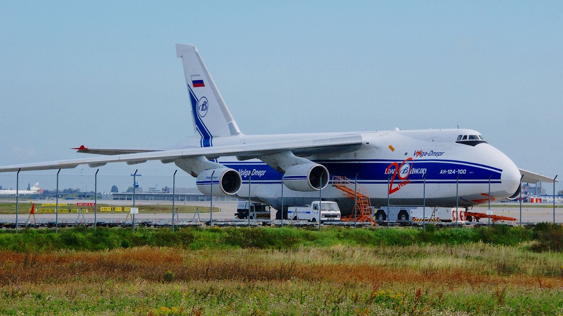 Large, white and blue cargo jet parked in remote section of airport.