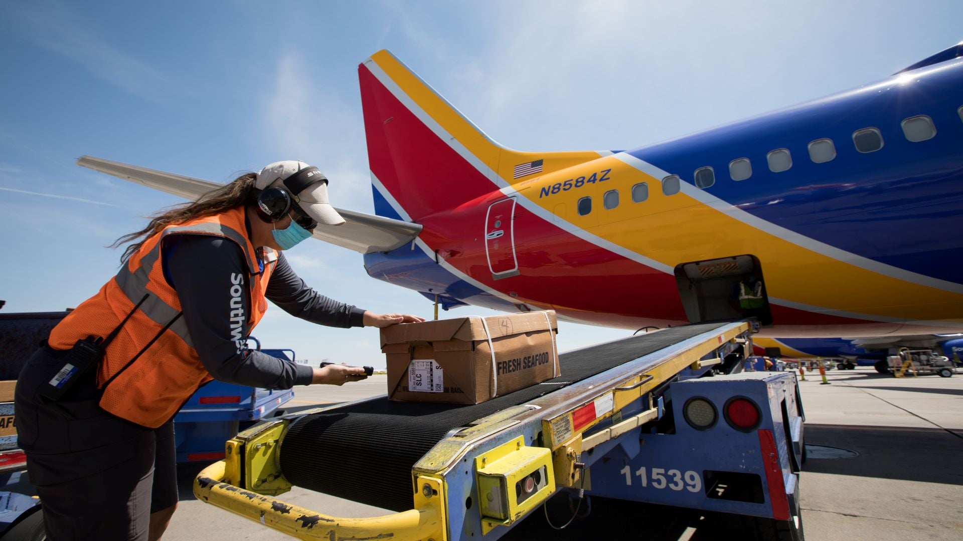 A person loads packages on a ramp into rear of a Southwest Airlines jet.