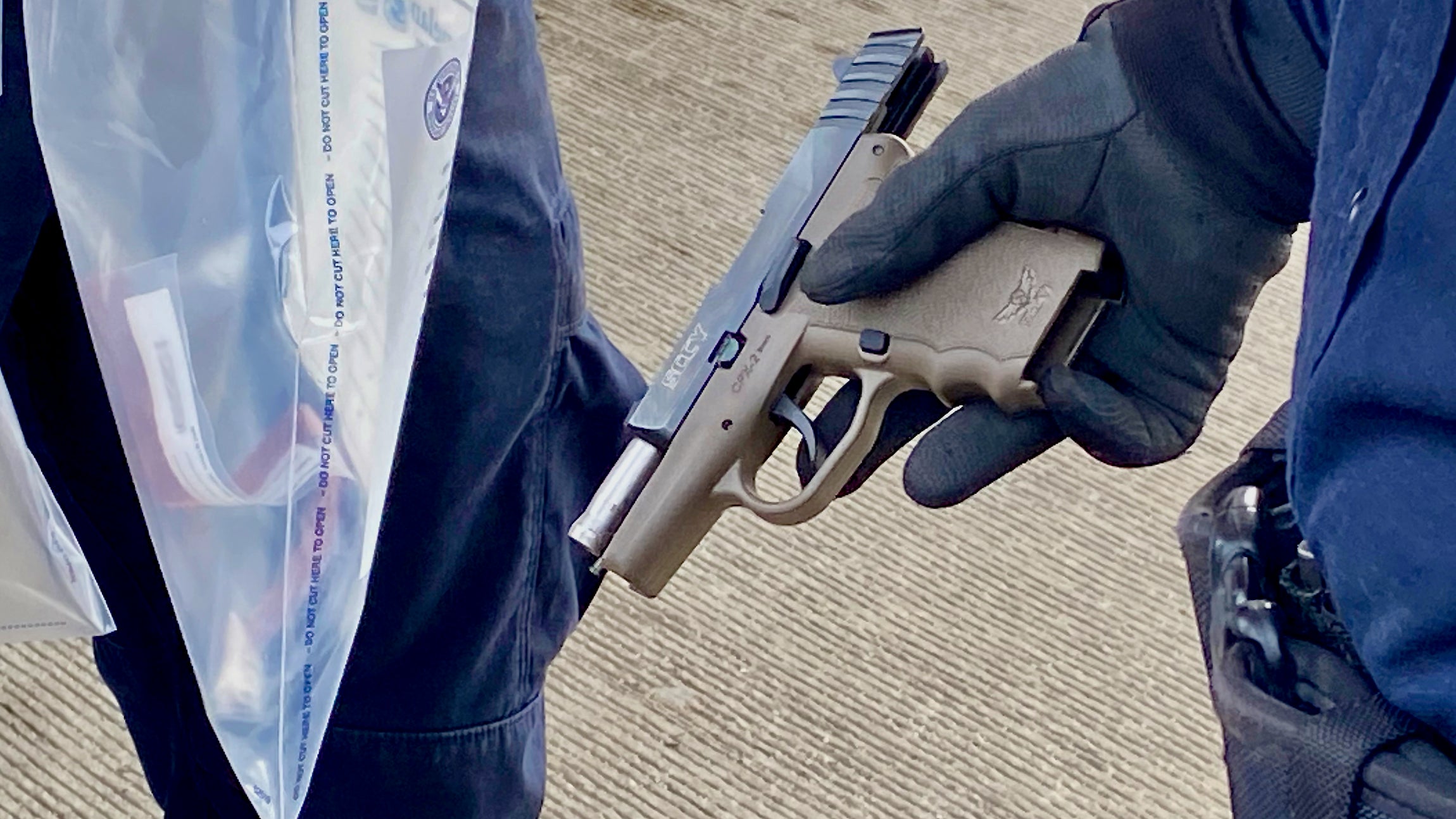 A CBP officer shows the gun seized from the cab of a truck at the US-Canada border. (Photo: CBP)