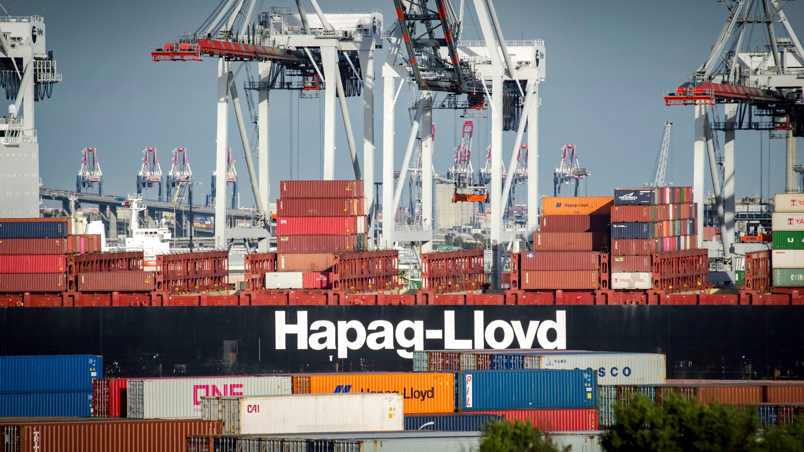 A container ship of Hapag-Lloyd seen from the side as shipping containers are being unloaded.