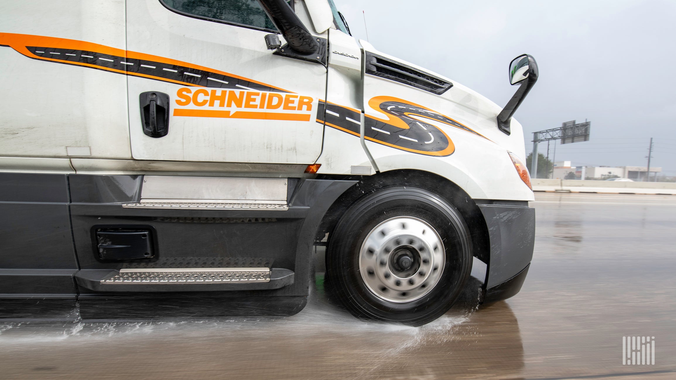 White Schneider tractor driving through heavy rain