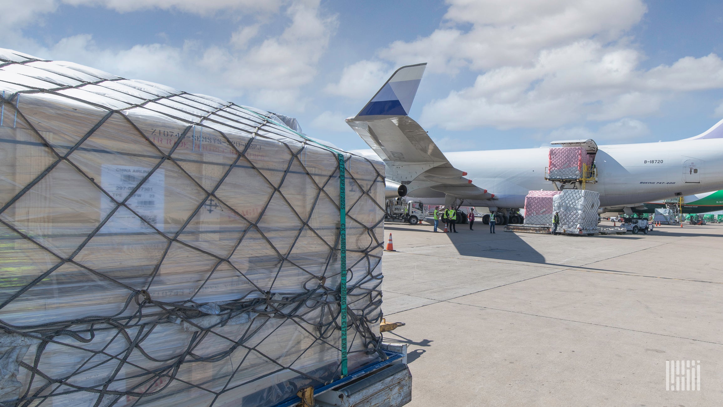 A pallet of cargo with netting sits on tarmac with a large freighter in the background. The air freight recovery stumbled in March because of the Ukraine war and other factors.