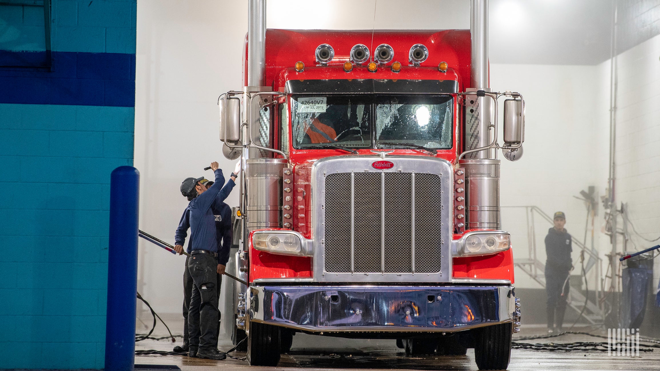 A man in a blue shirt inspects a red commercial truck