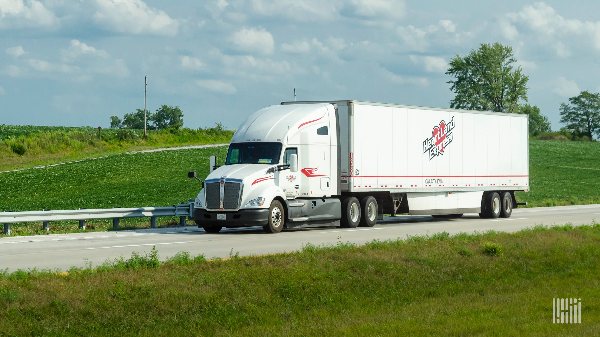 A white Heartland Express tractor and trailer on the highway