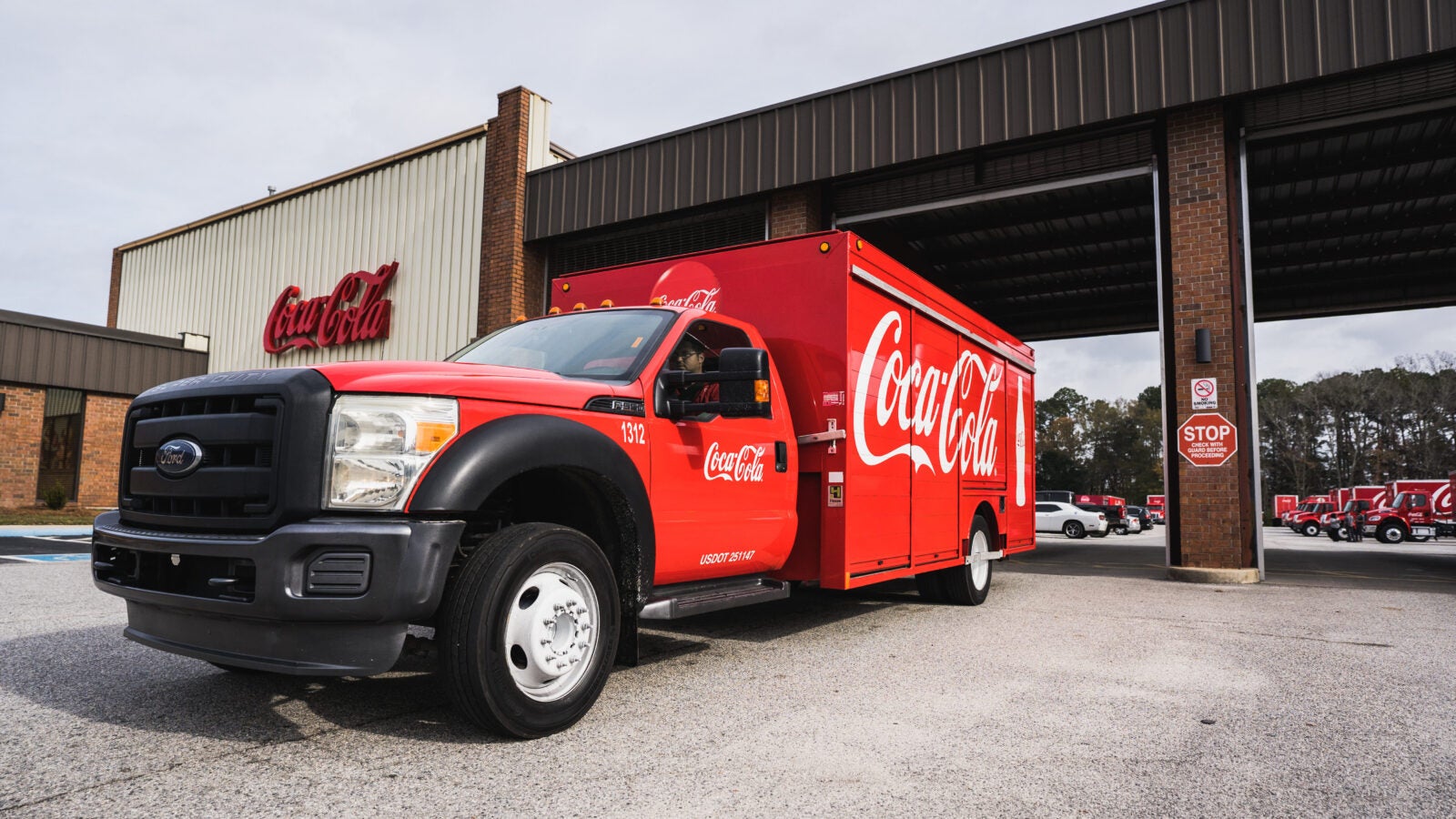 A red commercial truck and trailer with the logo of Coca-Cola on it.