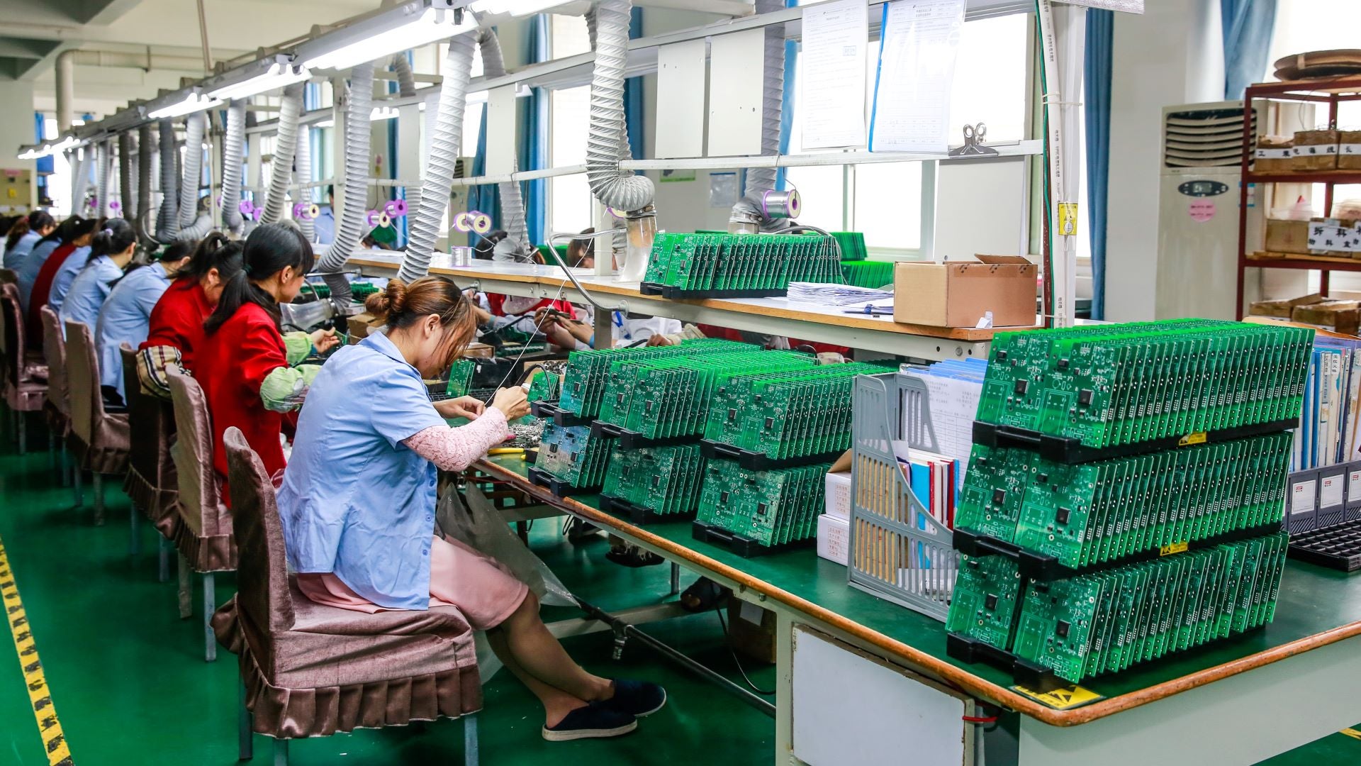 Factory workers in China making printed circuit boards. COVID restrictions are forcing factories to close, slowing deliveries to laptop and automakers.