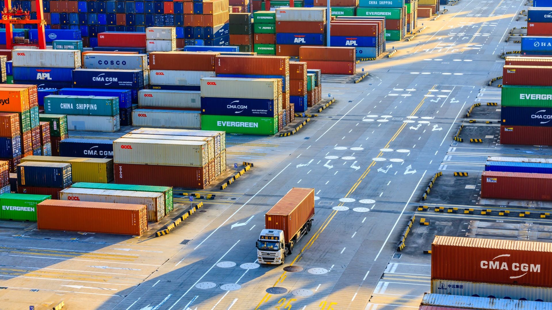 A tractor pulls a container through a container shipping yard in Shanghai, where COVID restrictions are slowing trade.