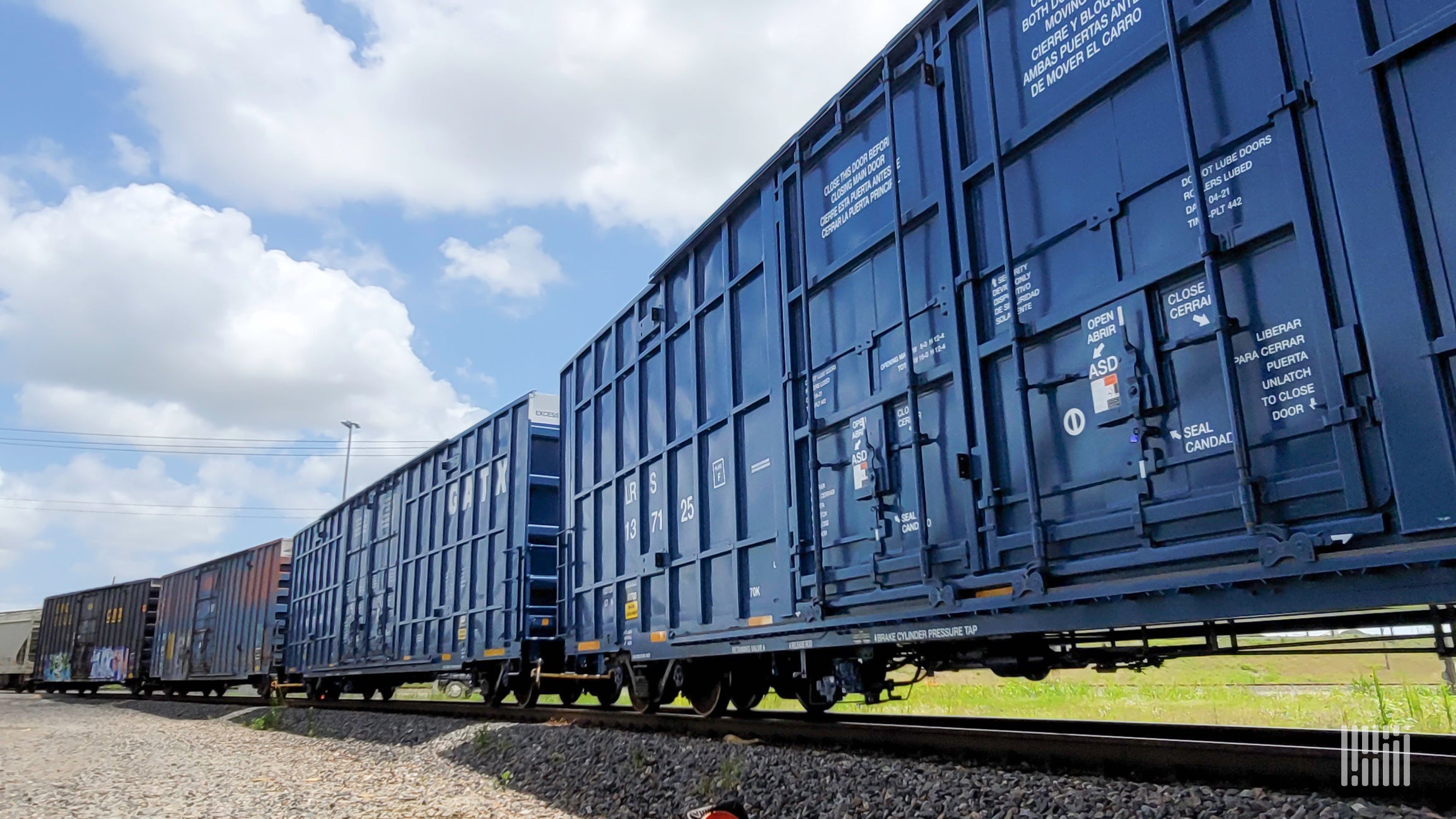 A photograph of railcars traveling along a field.