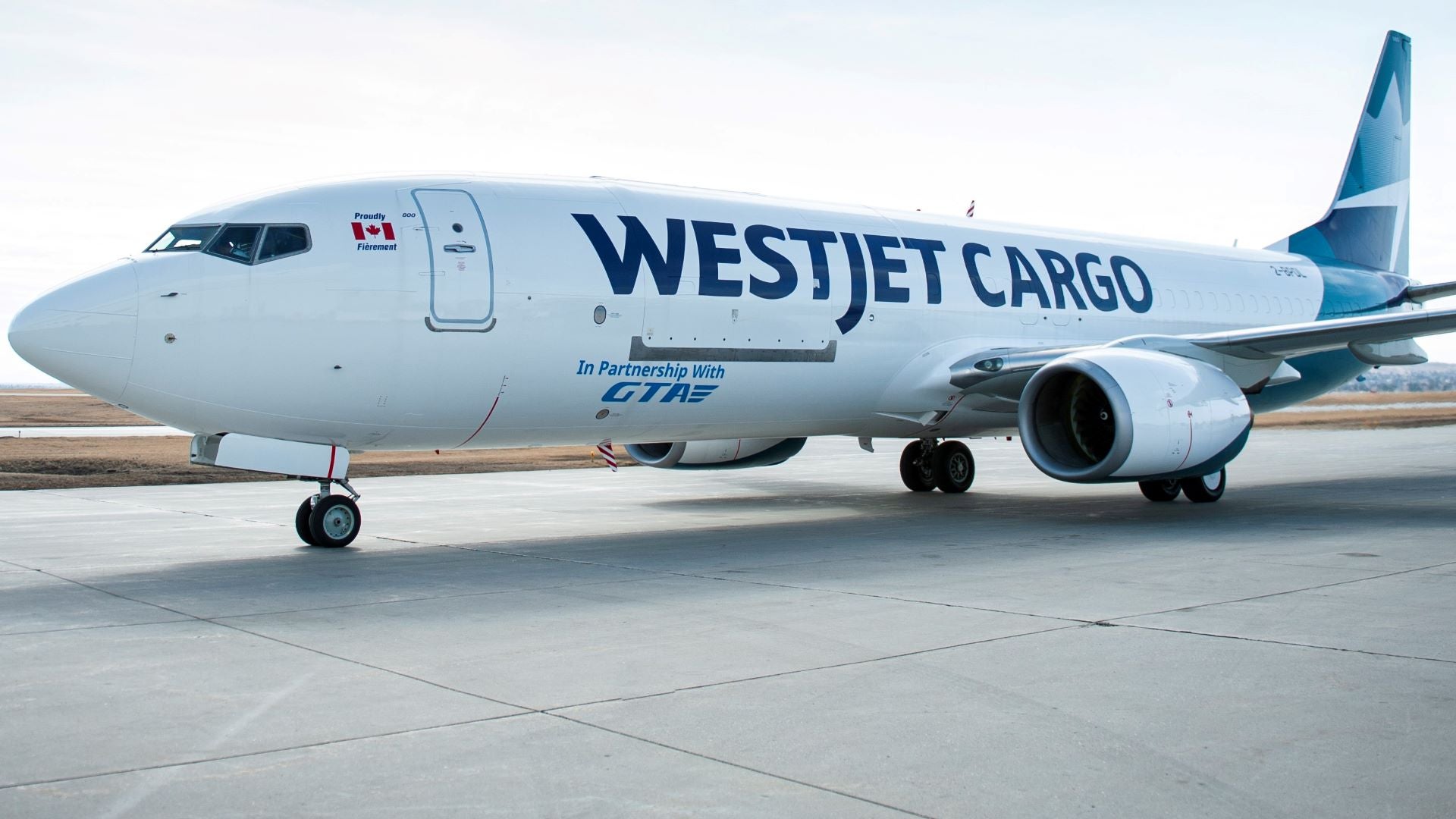 A white jet with teal tail and WestJet Cargo painted on fuselage. The aircraft is WestJet's first freighter.