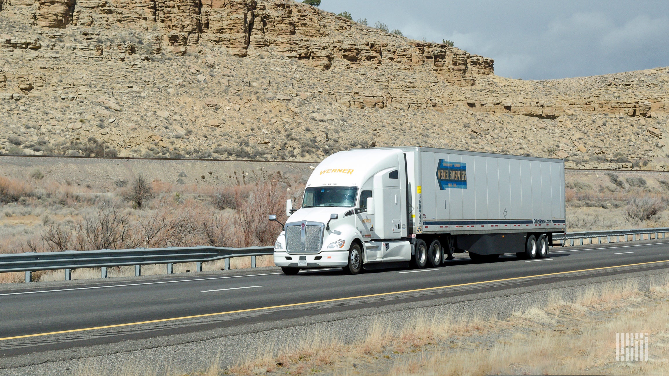 A white Werner tractor with a white trailer on the highway