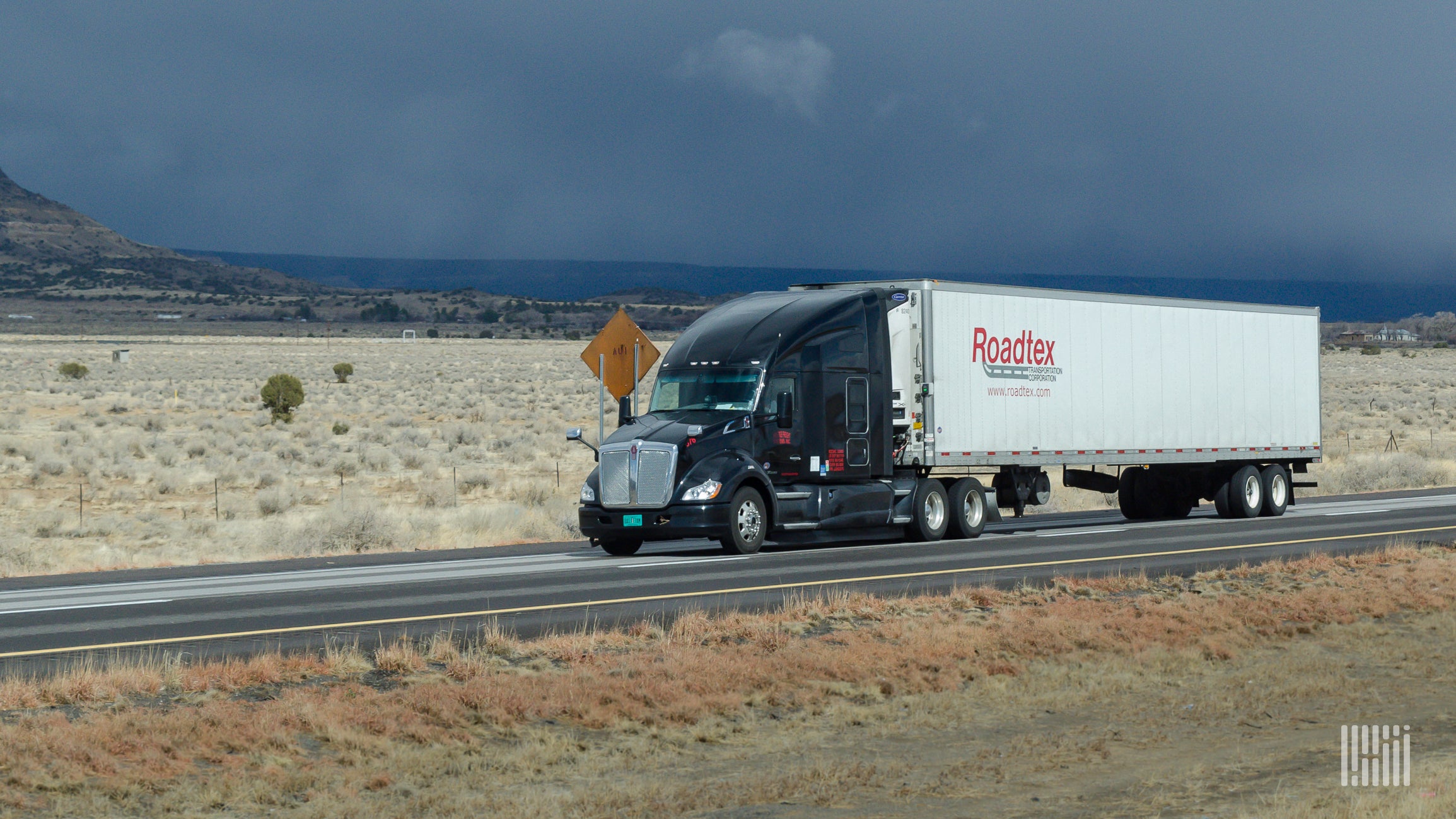 Black tractor and white Roadtex trailer on highway