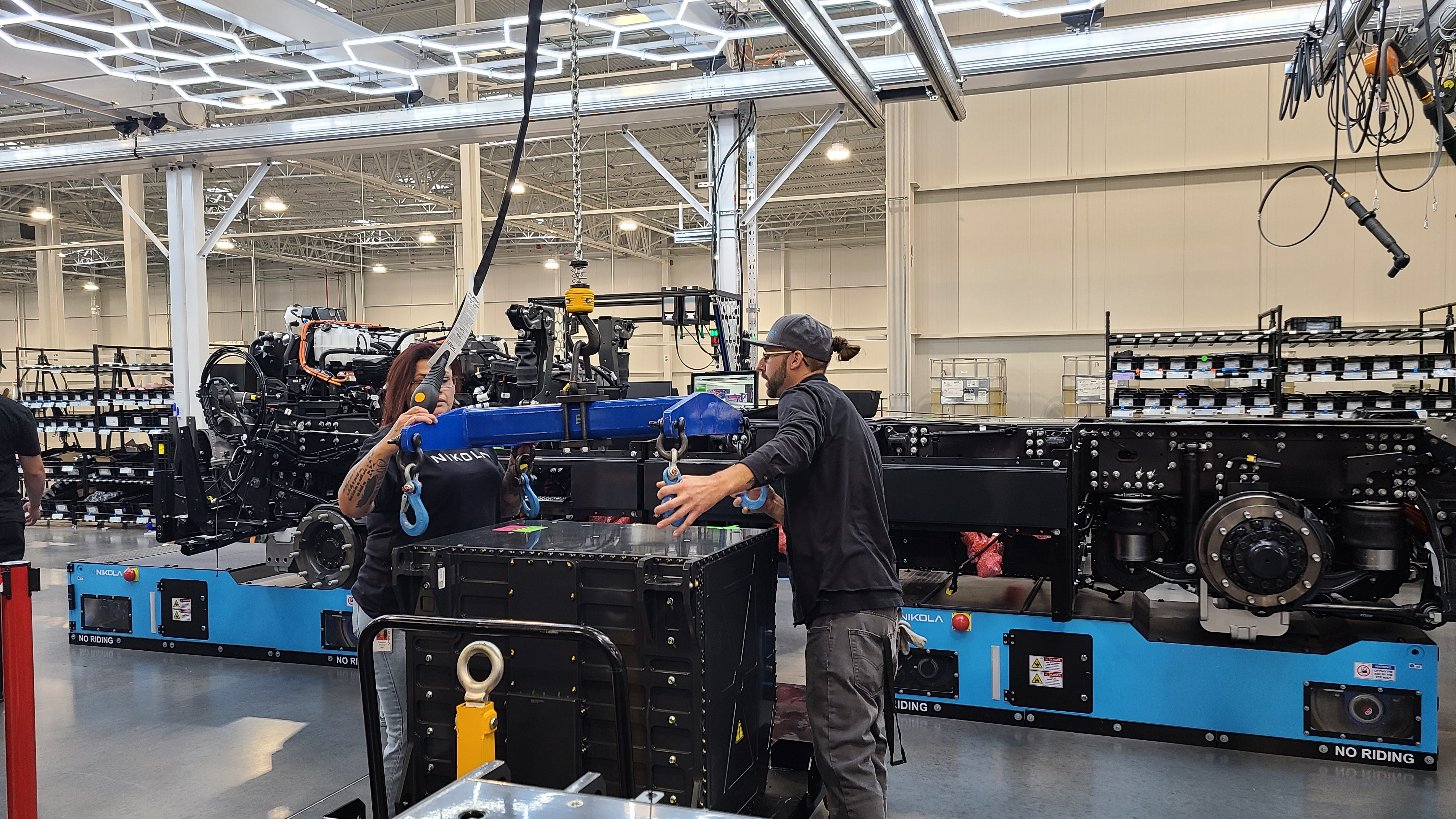 Nikola workers move battery pack into place for Nikola electric truck.