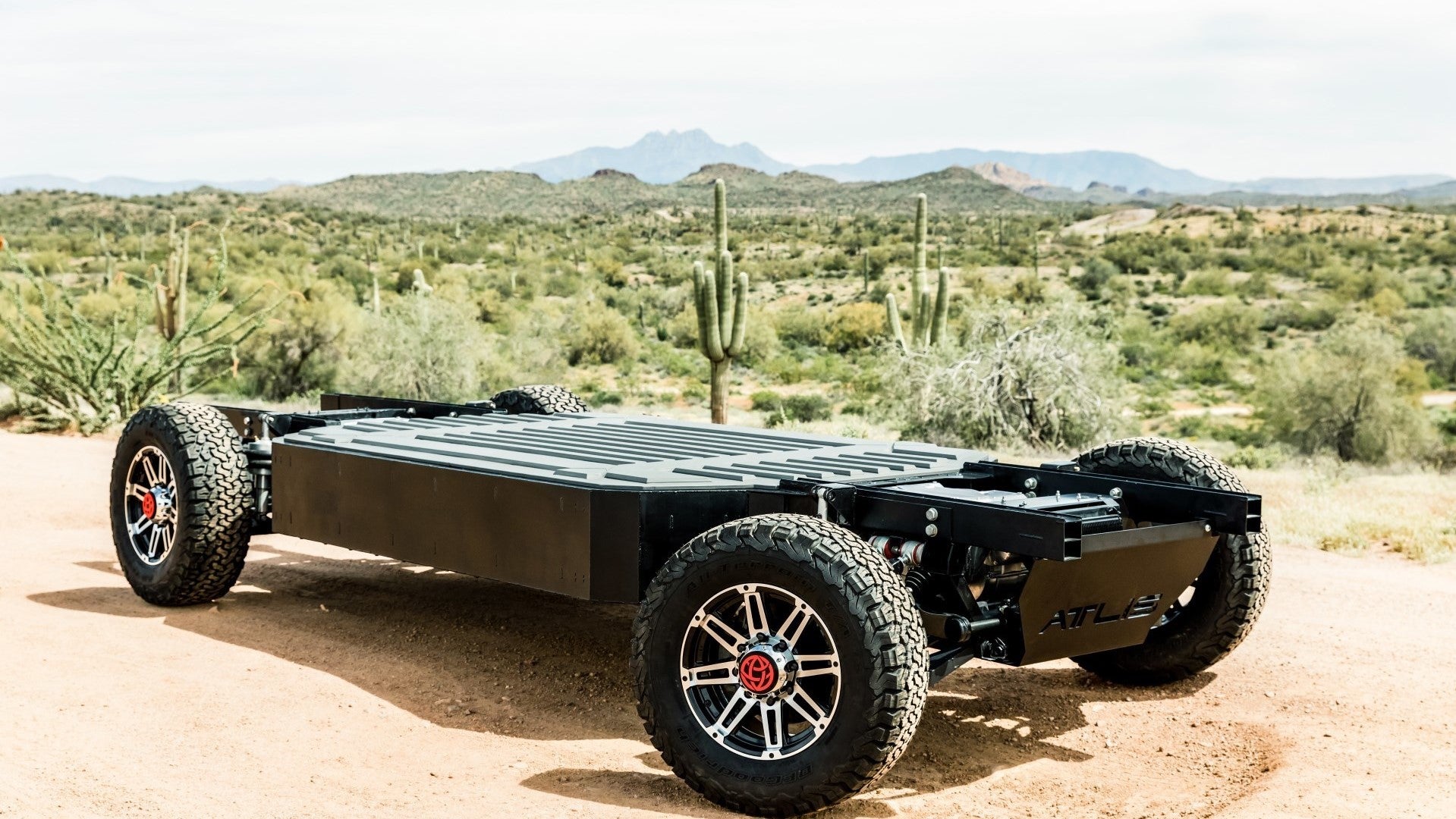 A three-quarters view of the flat-floor electric chassis that makes up the Atlis XP platform sitting in desert scrub