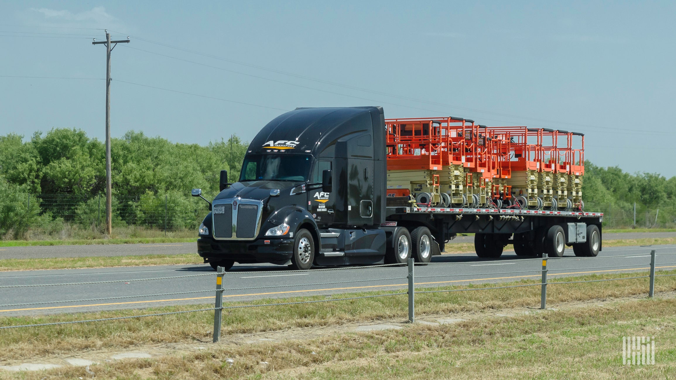 A black AFC Transport tractor trailer is traveling down a major road.