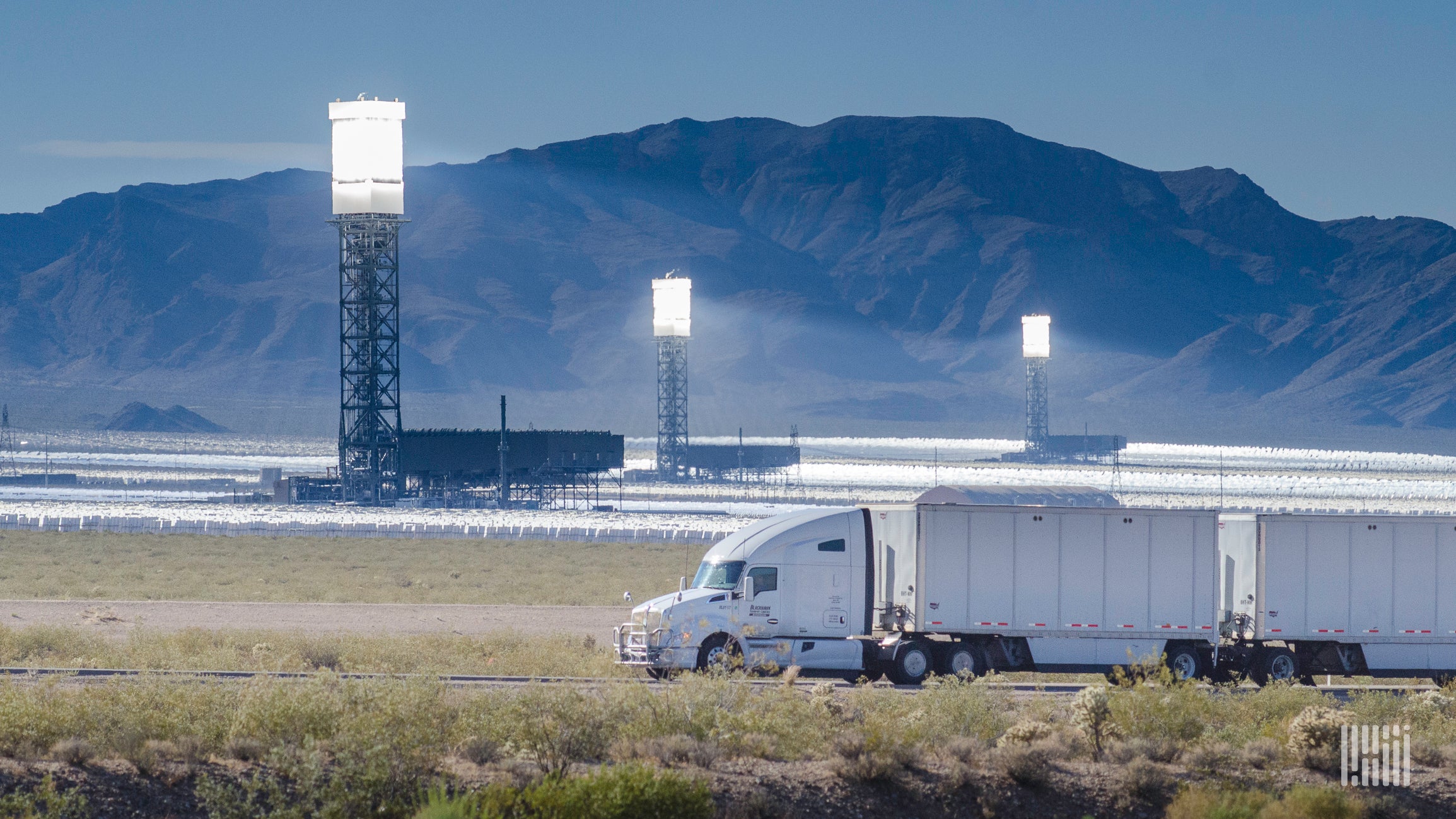 LTL rig on highway with solar thermal power plant in the background