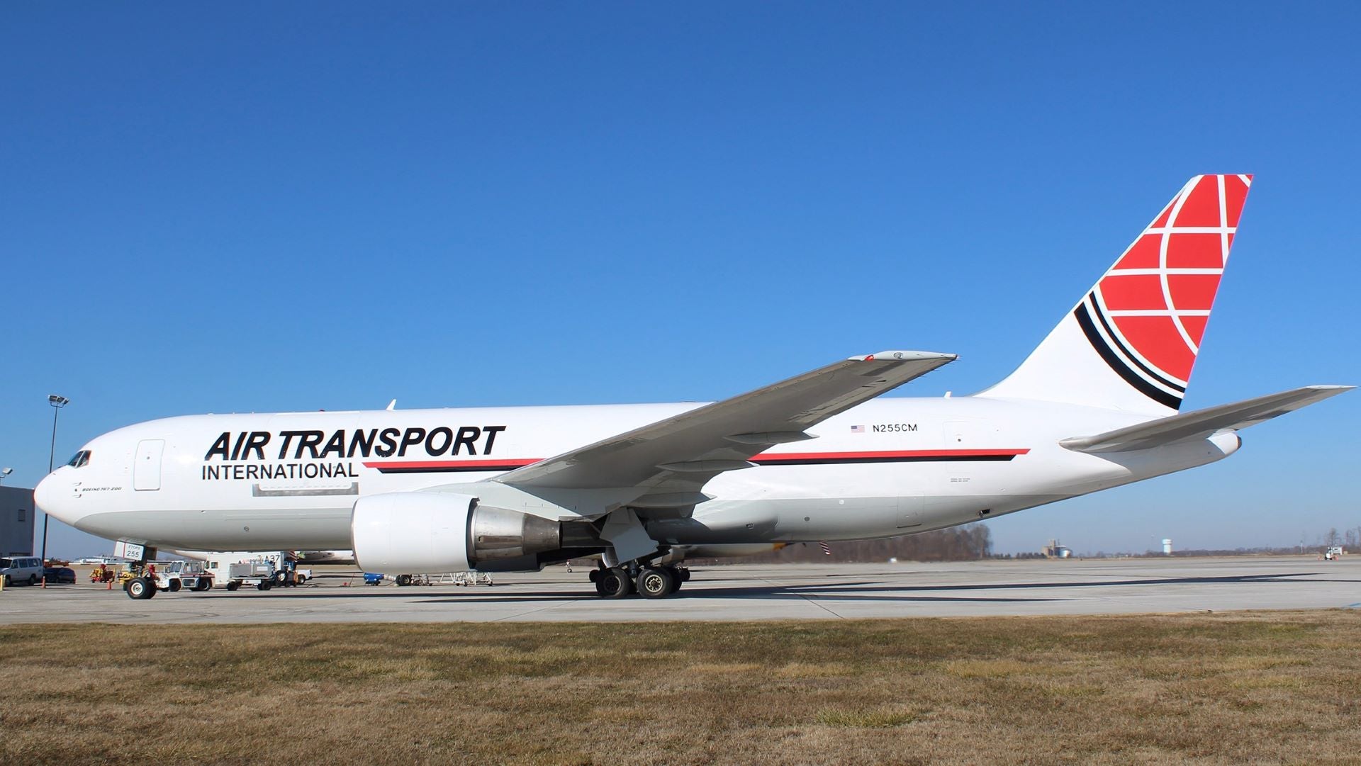 Sideview of big white jet with red tail and Air Transport International written on the fuselage. Sunny day with blue sky.