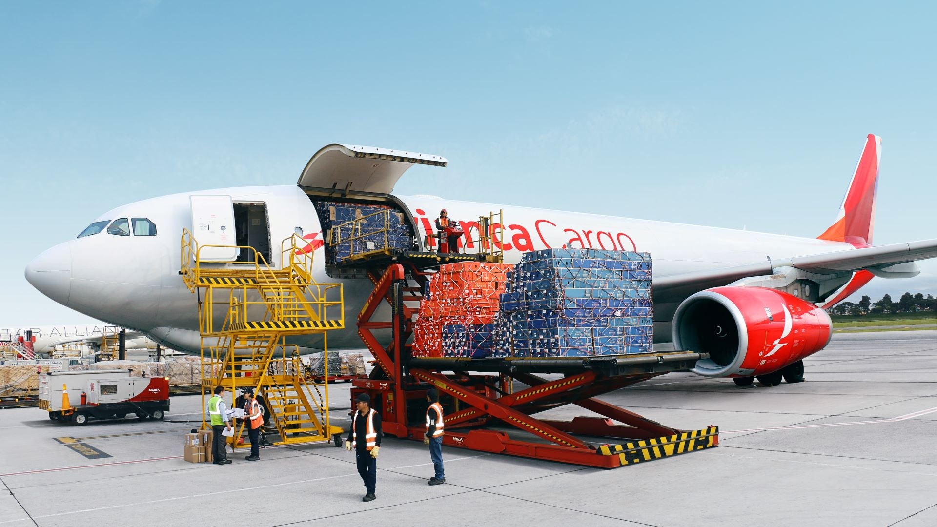 A white jet with red accents is loaded with cargo through a side door.