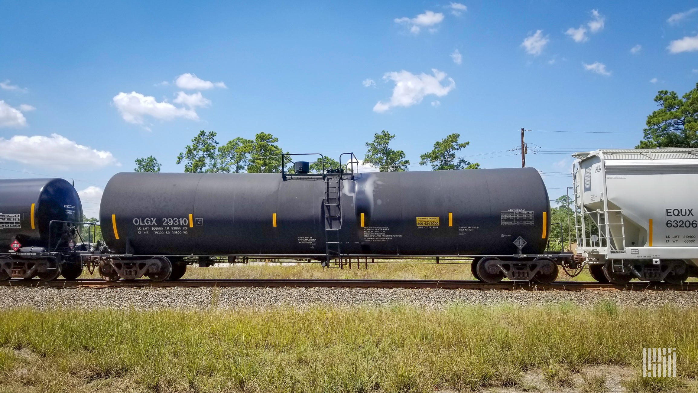 Two tank cars and a hopper car travel on the railroad.