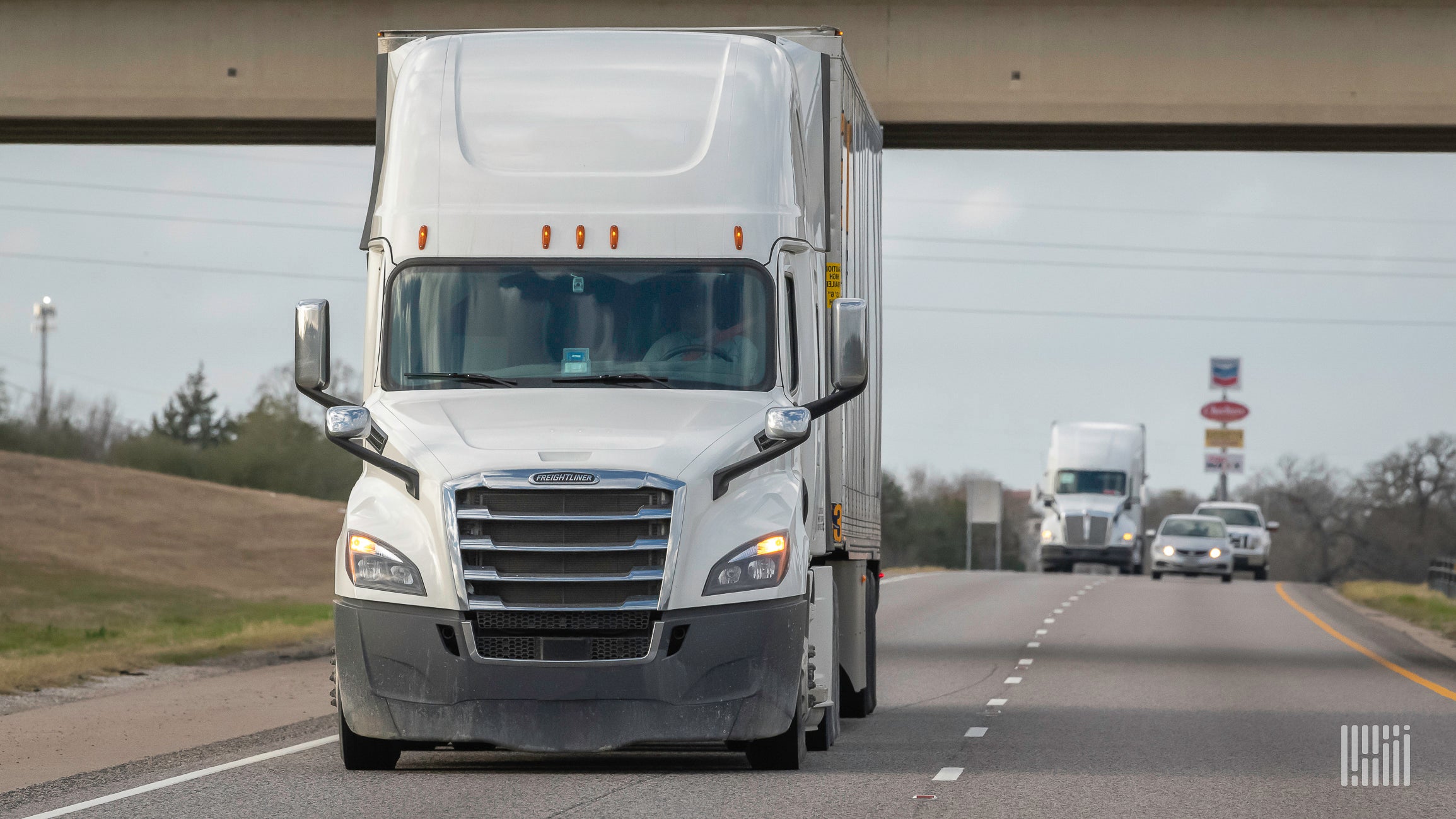 A white tractor hauling a white trailer on the highway