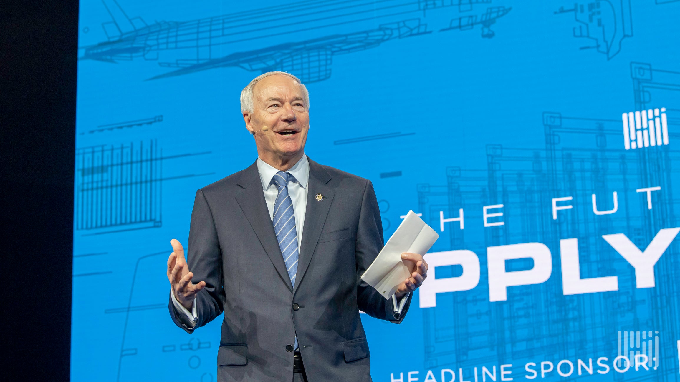 A close-up of Arkansas Governor Asa Hutchinson with arms outstretched talking to an audience.