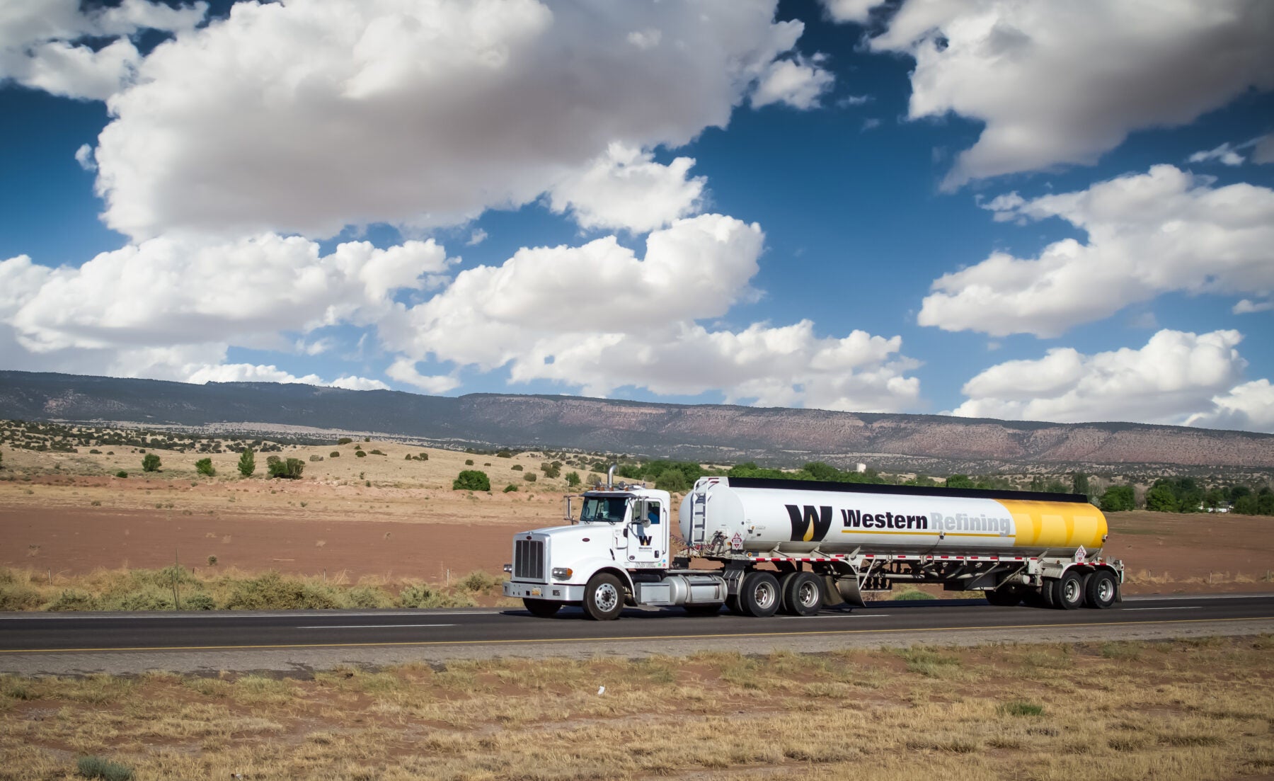 A fuel tanker truck traveling on a highway in the desert