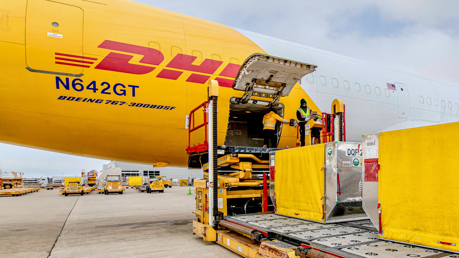 A cargo plane with the logo of is unloaded by men at an airport.