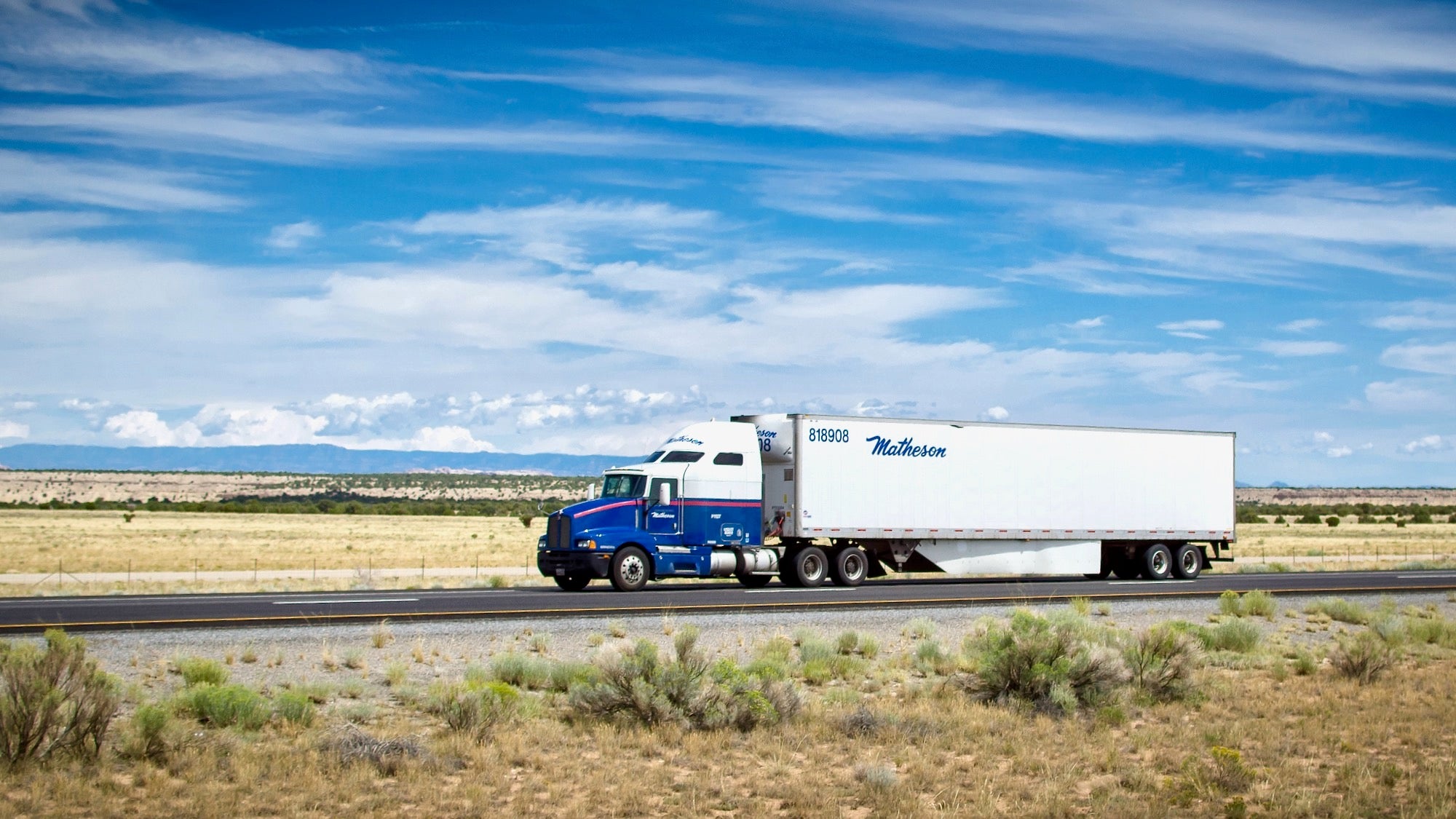 A tractor-trailer with logo of Matheson Postal Services travels on a highway.