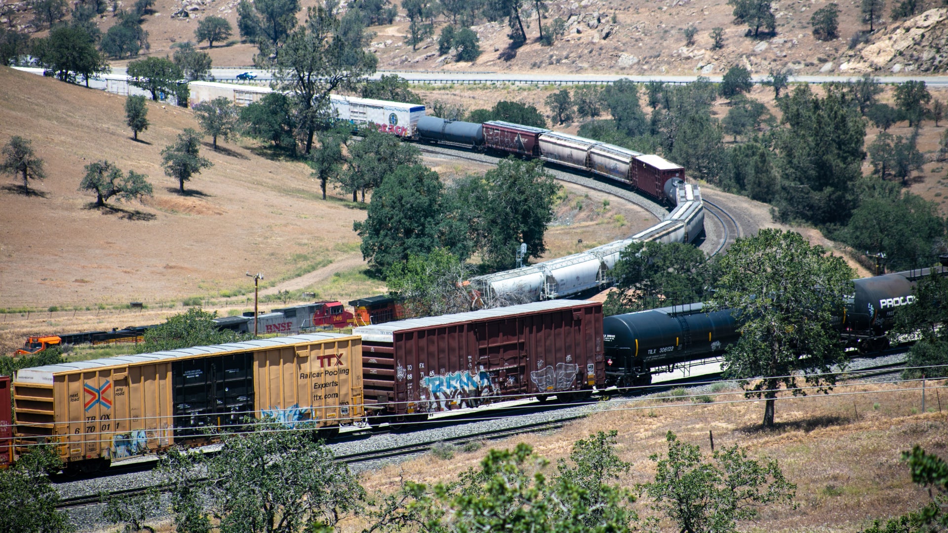 A freight train weaves through a hilly desert.