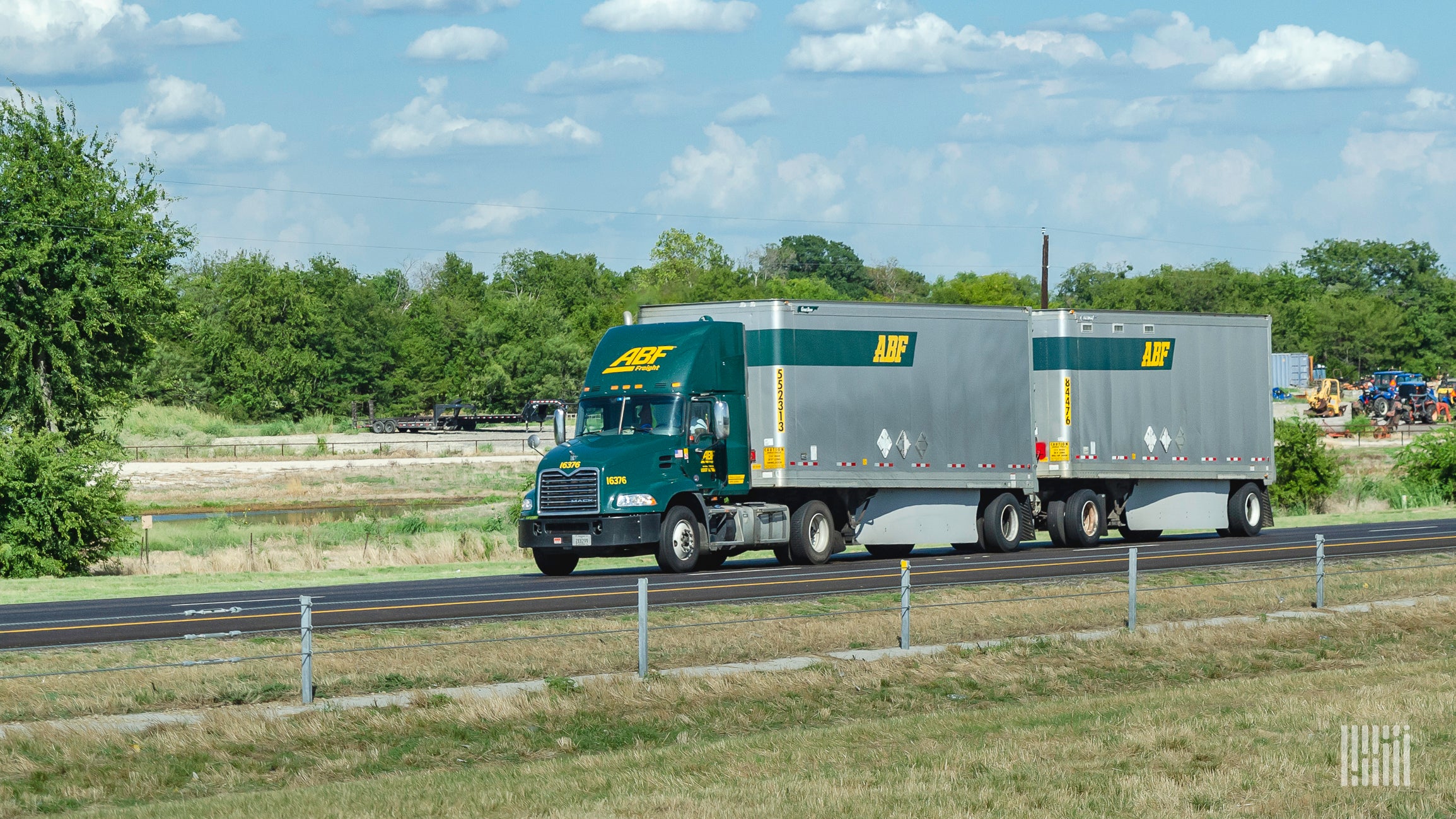 A green ABF Freight tractor pulling two silver ABF Freight trailers